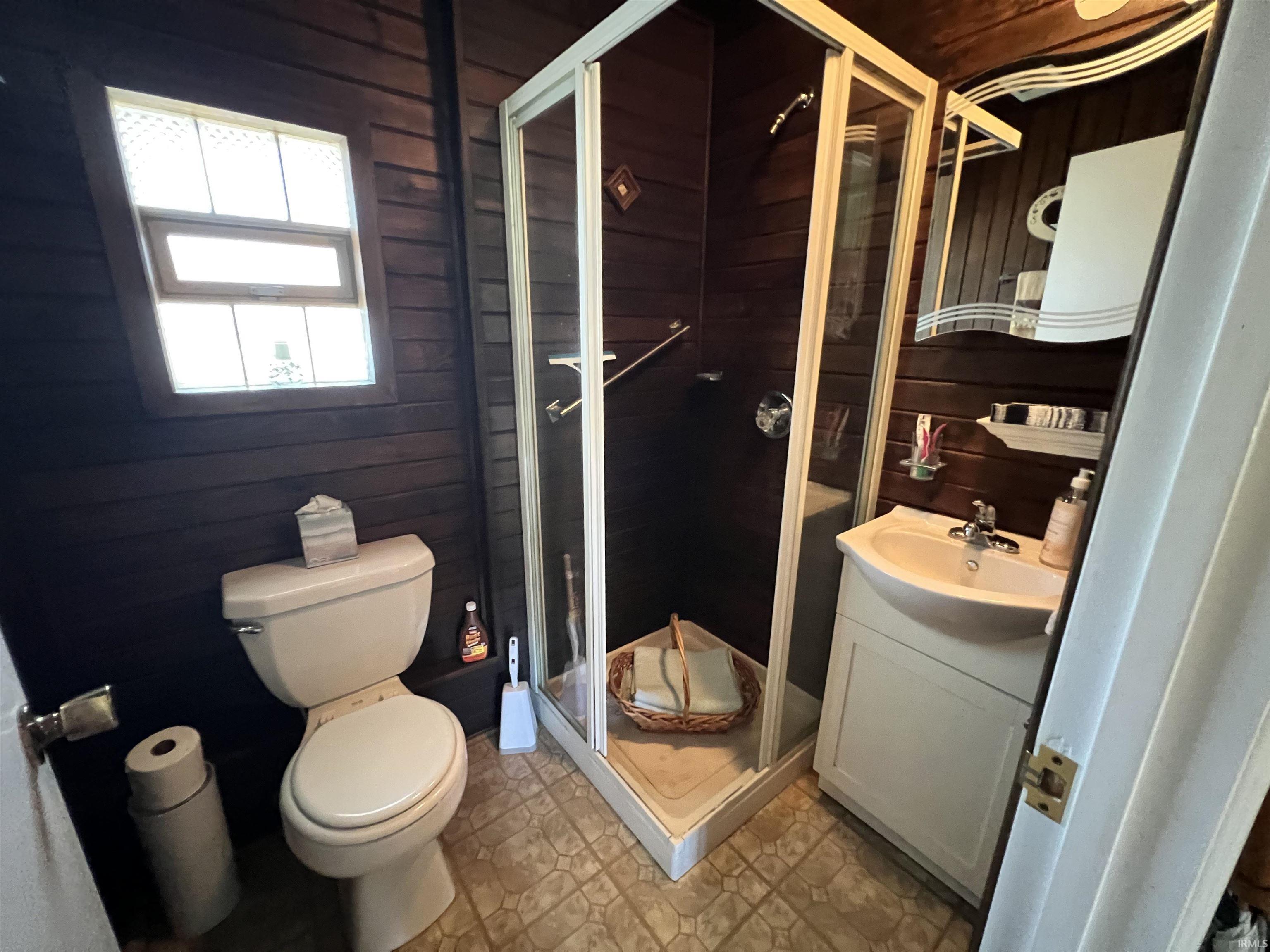 Compact bathroom featuring a corner shower with glass enclosure, a toilet, and a vanity with an integrated sink