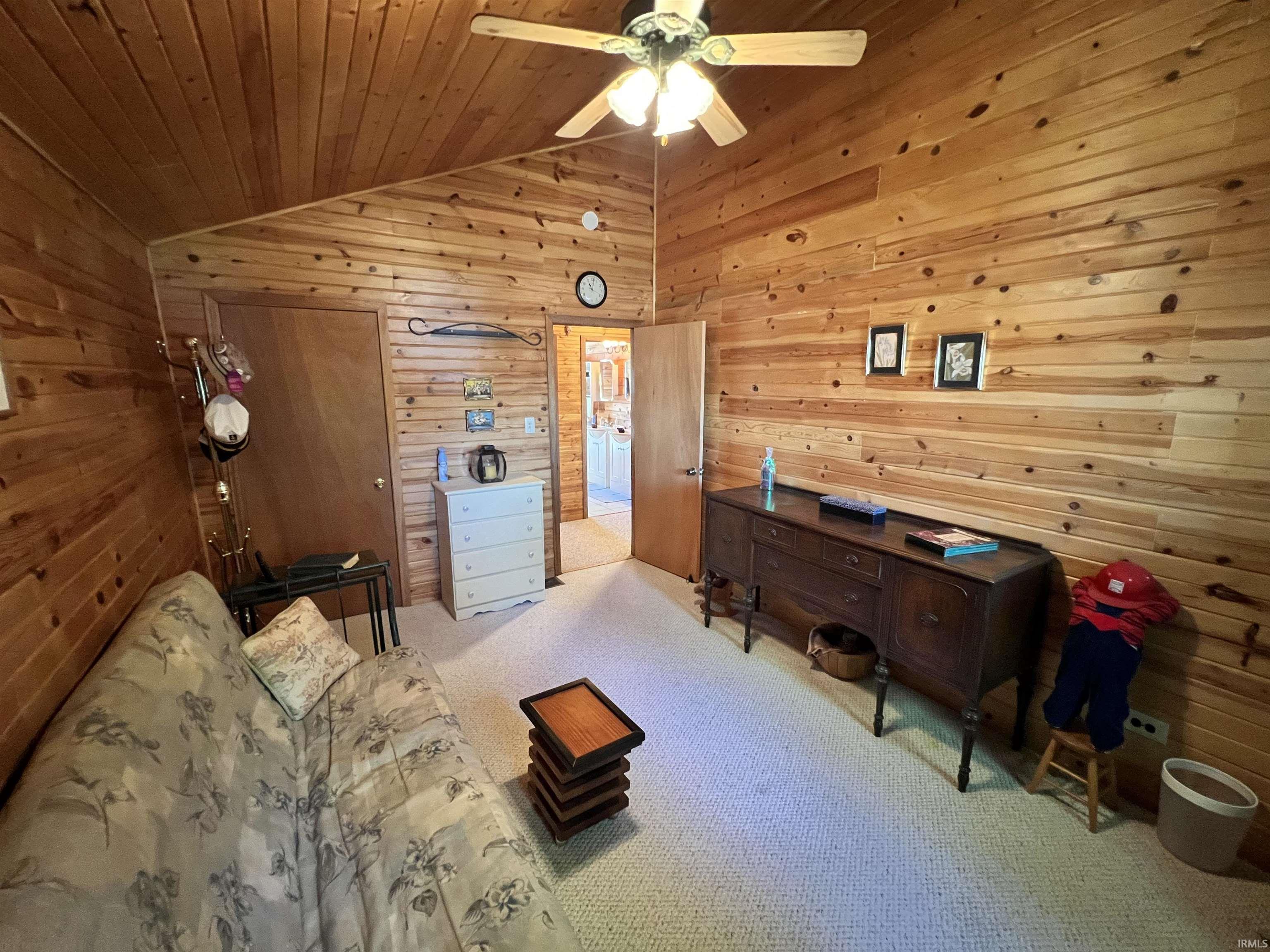 Vaulted wood-paneled ceiling complemented by matching wood-paneled walls, featuring a ceiling fan with integrated lighting