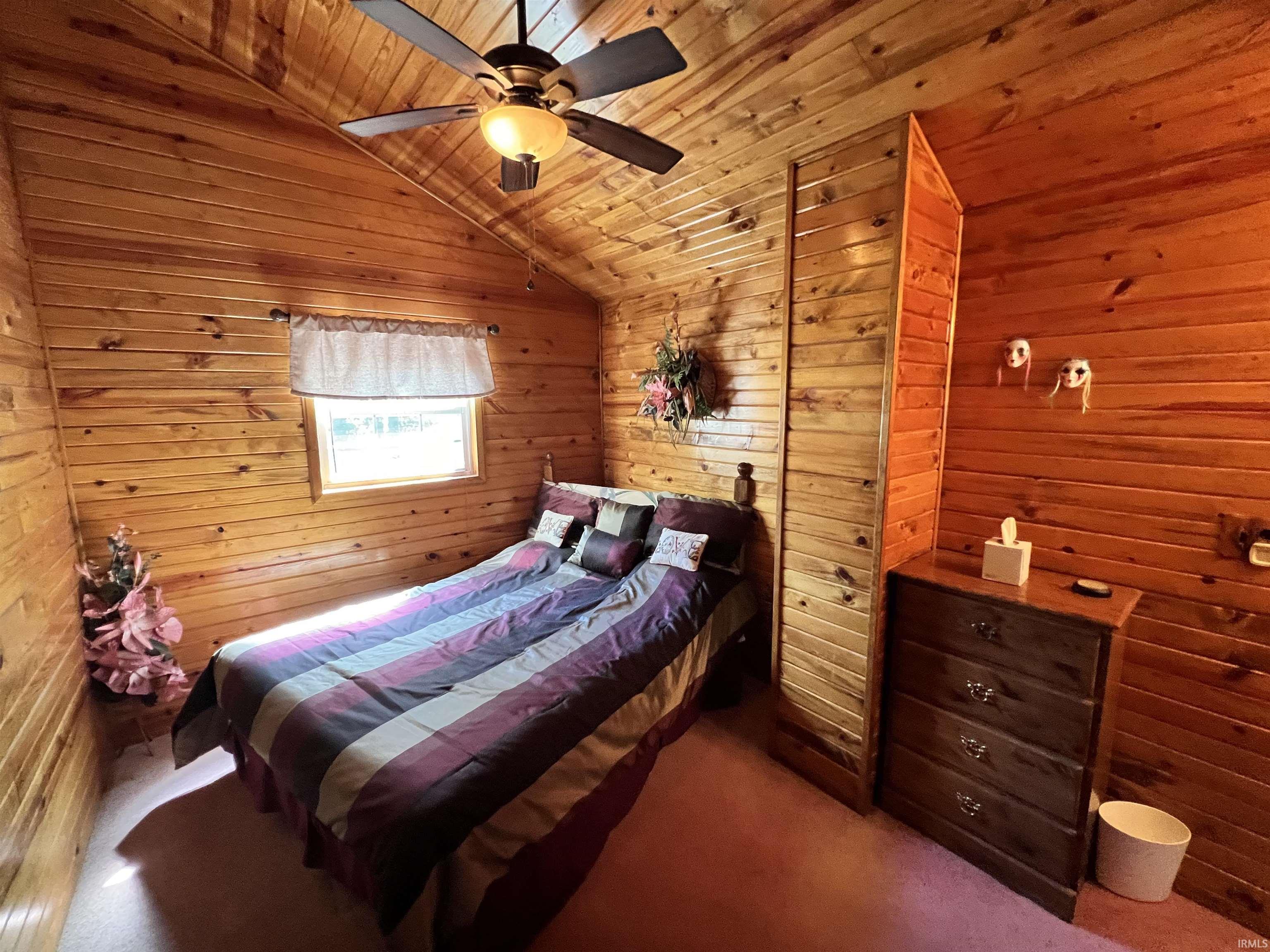 Wood-paneled room featuring an angled ceiling and a single window