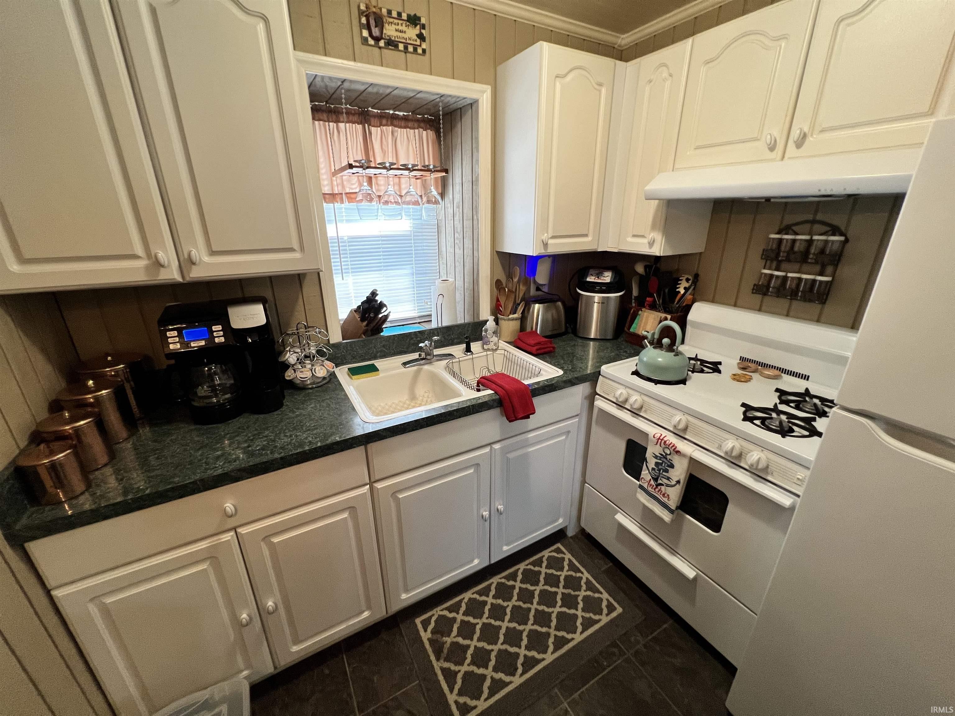 Kitchen featuring white cabinetry, a double basin sink, green countertop, and dark flooring