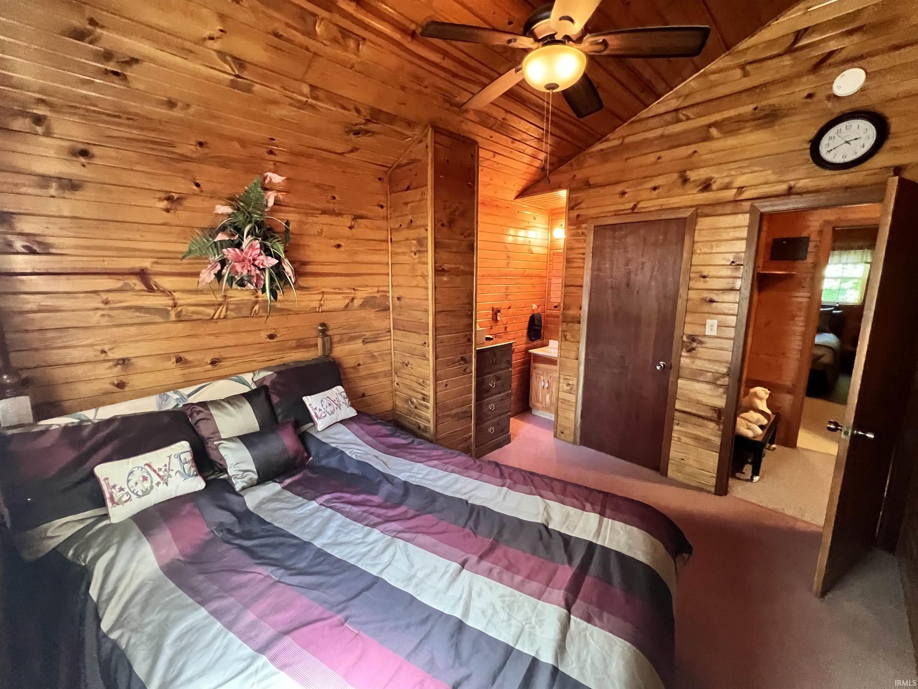 Wood-paneled walls and vaulted ceilings featuring a ceiling fan with integrated lighting