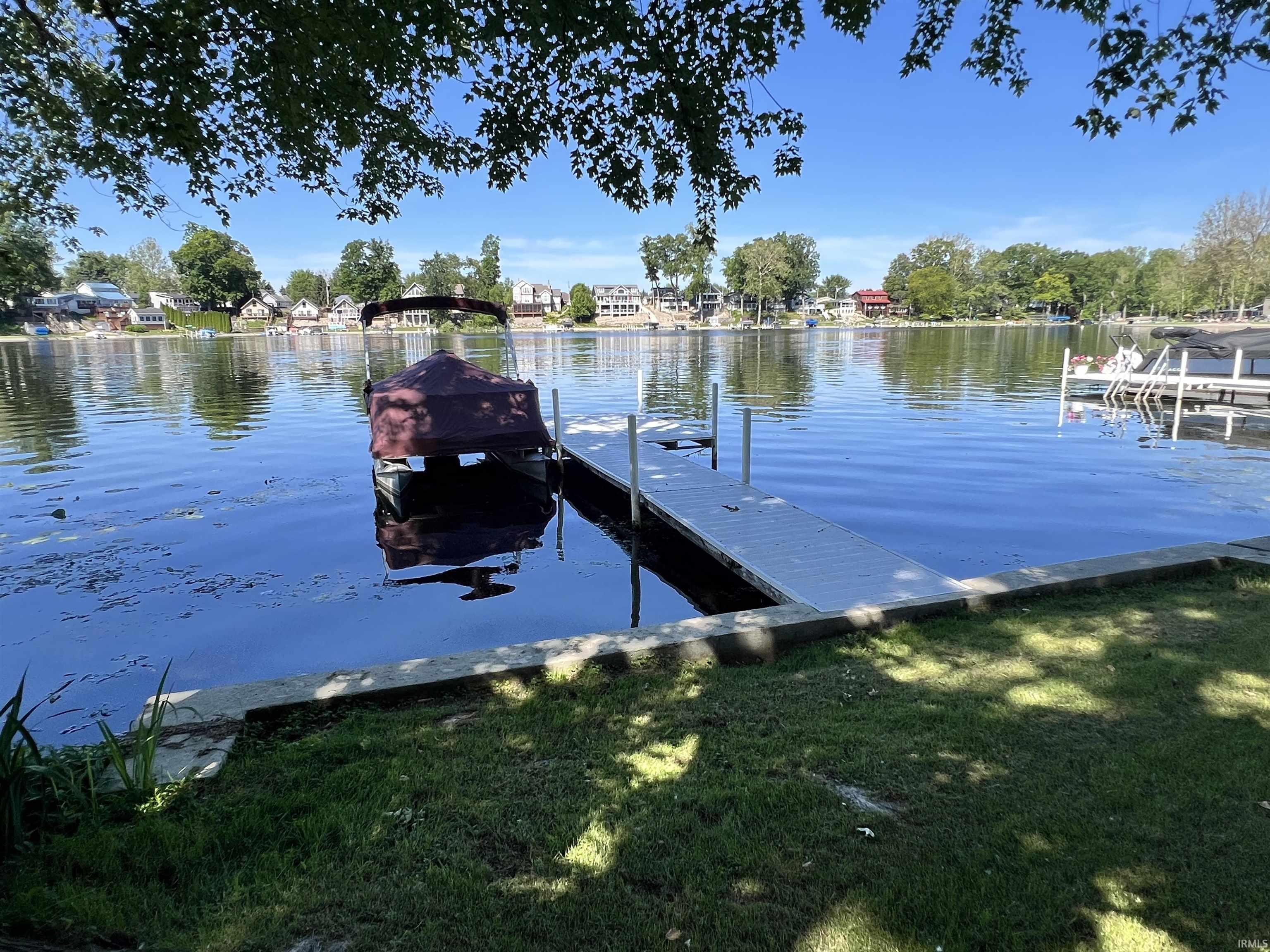 Waterfront property featuring a private dock, direct lake access, and a grassy shoreline