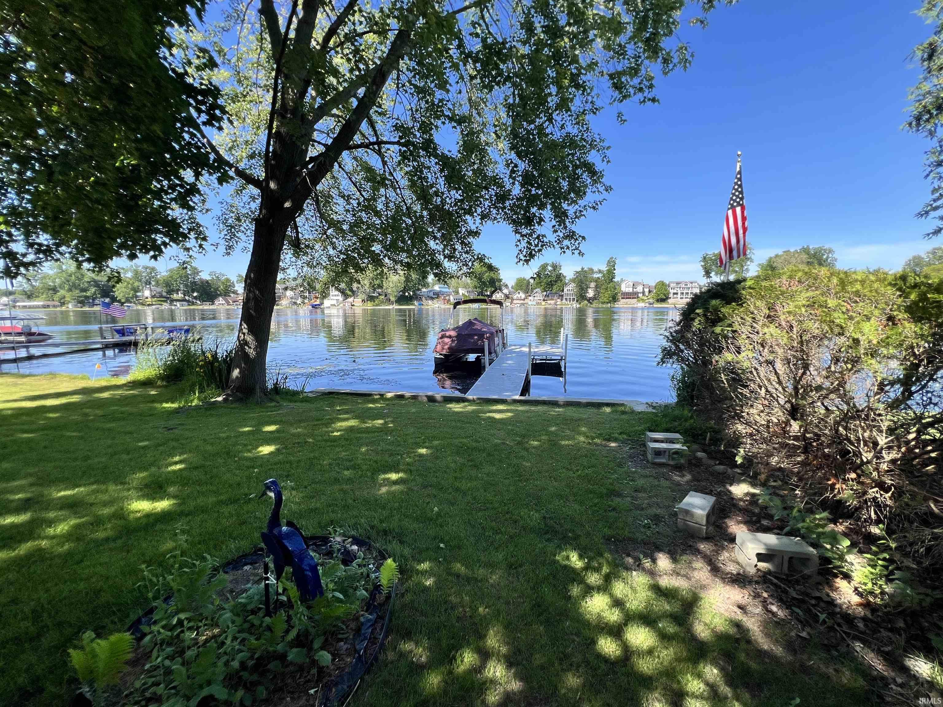 Lakeside property featuring a boat dock, concrete retaining wall, and manicured lawn