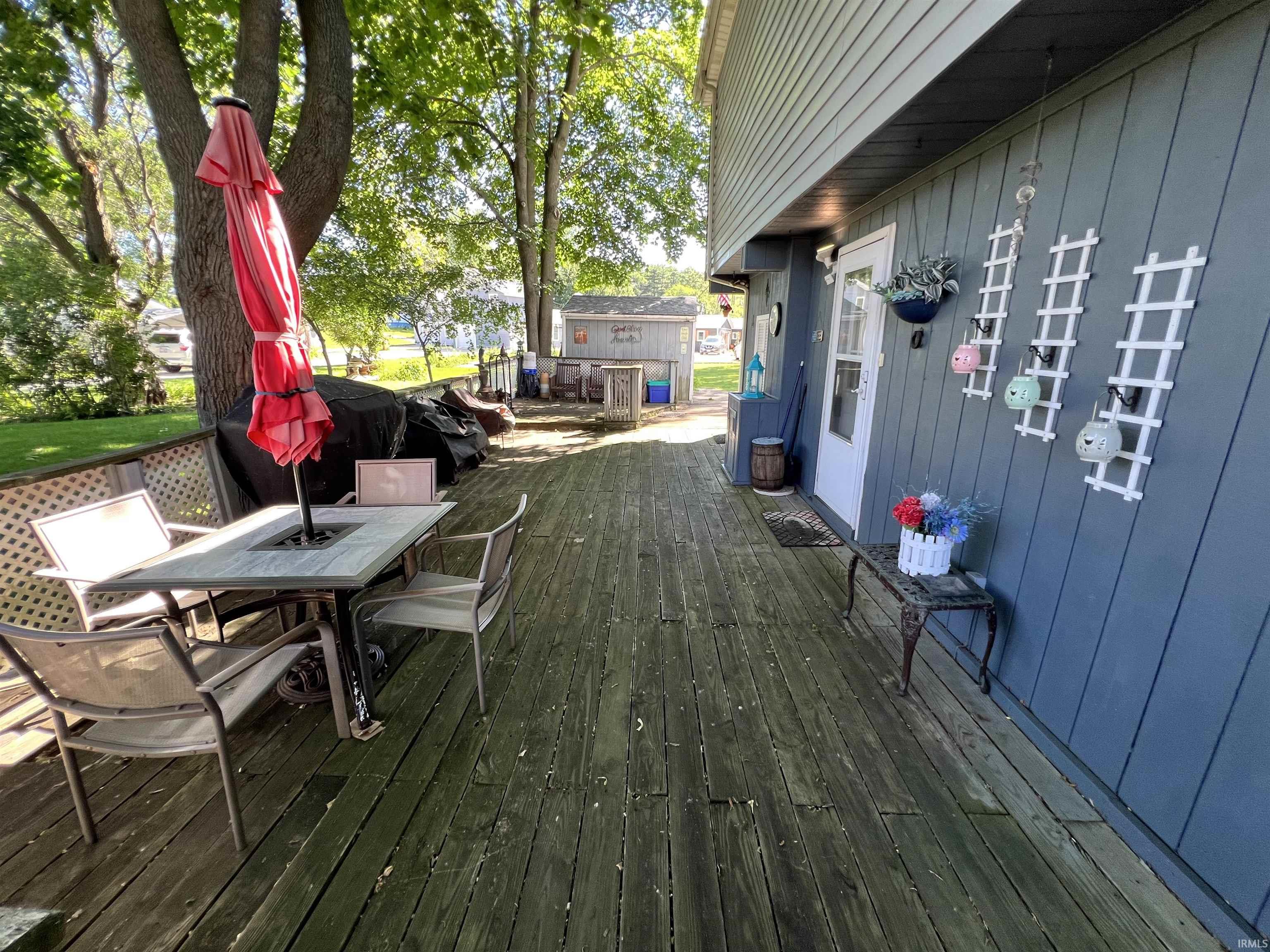 Expansive wood deck with direct exterior access, featuring a mature shade tree and horizontal siding