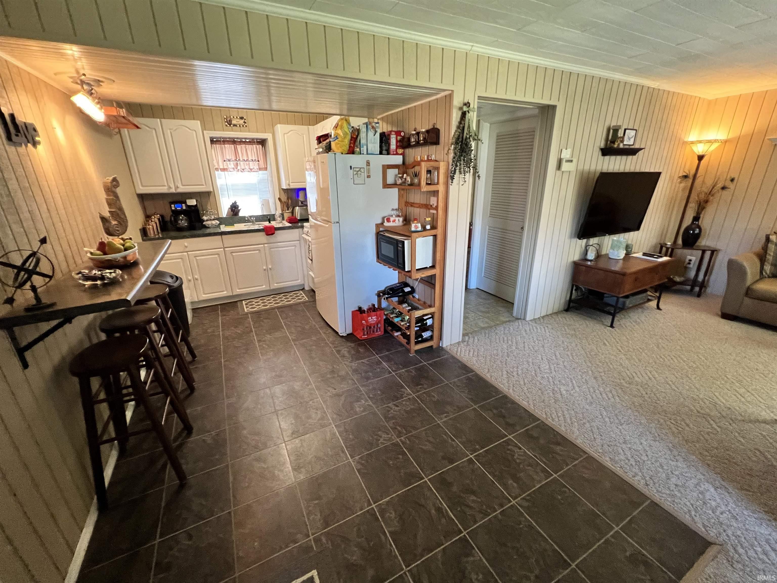 Galley kitchen featuring white cabinetry, dark countertops, and tile flooring
