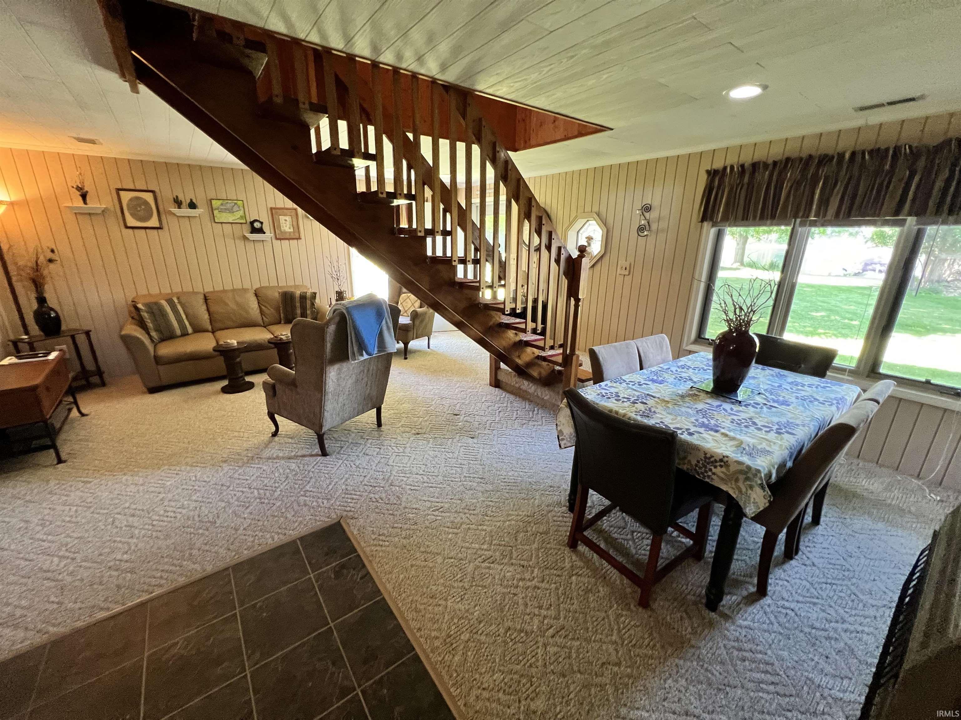 Open-concept living space with a prominent wood staircase and wood-paneled walls