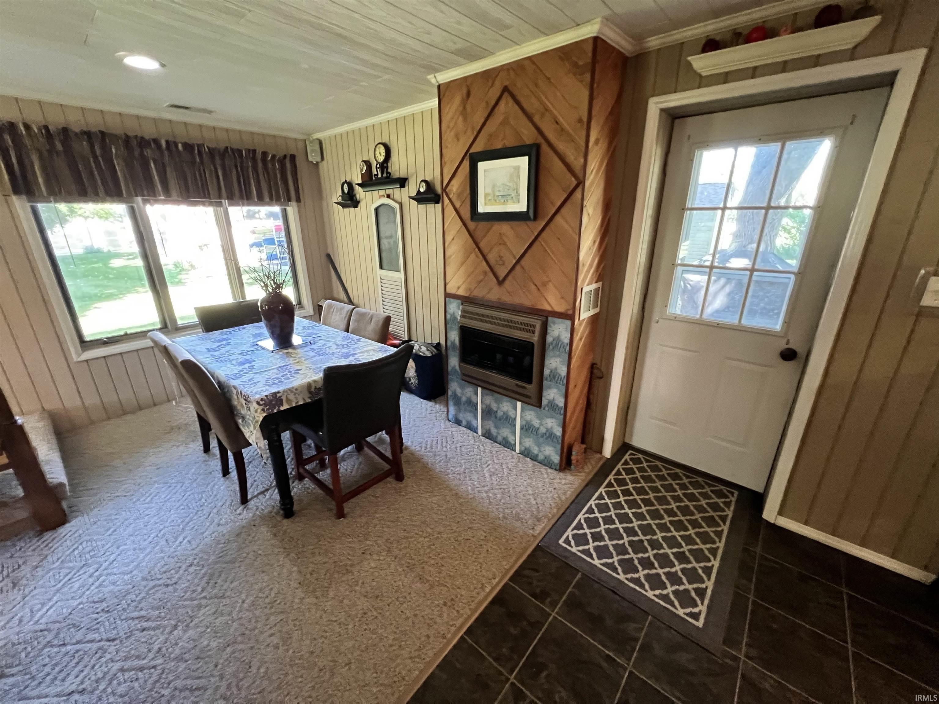Dining area featuring a built-in fireplace with a tile surround, wood-paneled accent wall, and a large window