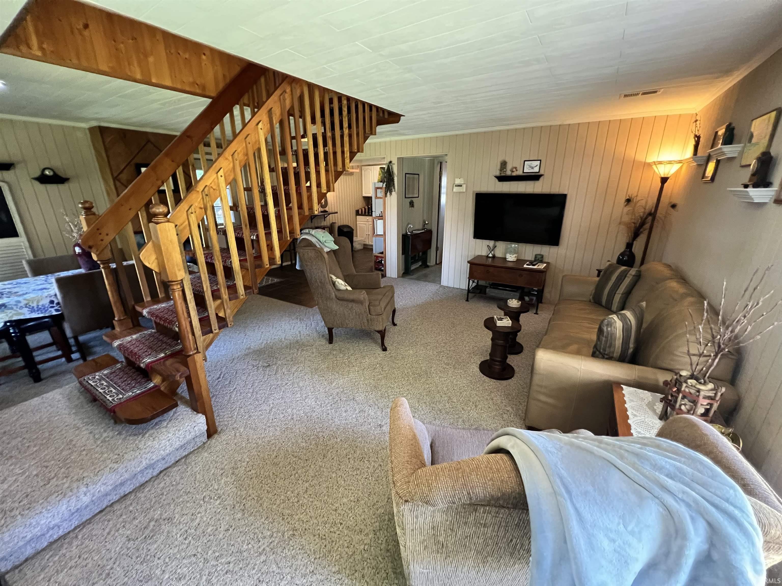 Open-concept living area with a prominent wood staircase and wood-finish paneling