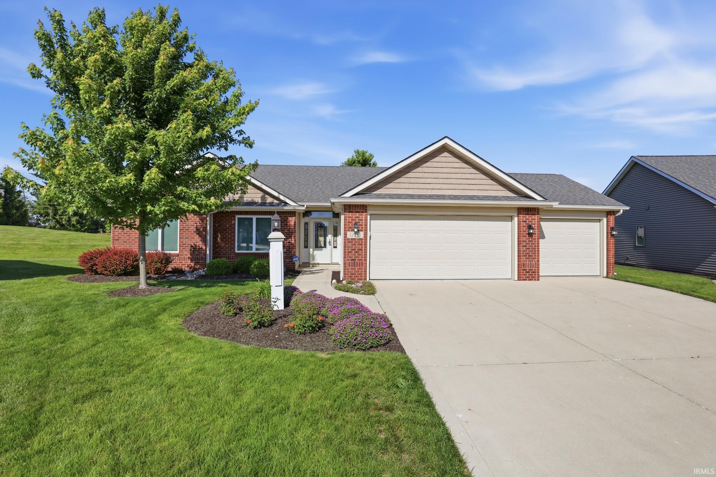 Brick exterior featuring a two-car garage with individual doors, gabled rooflines, and a concrete driveway