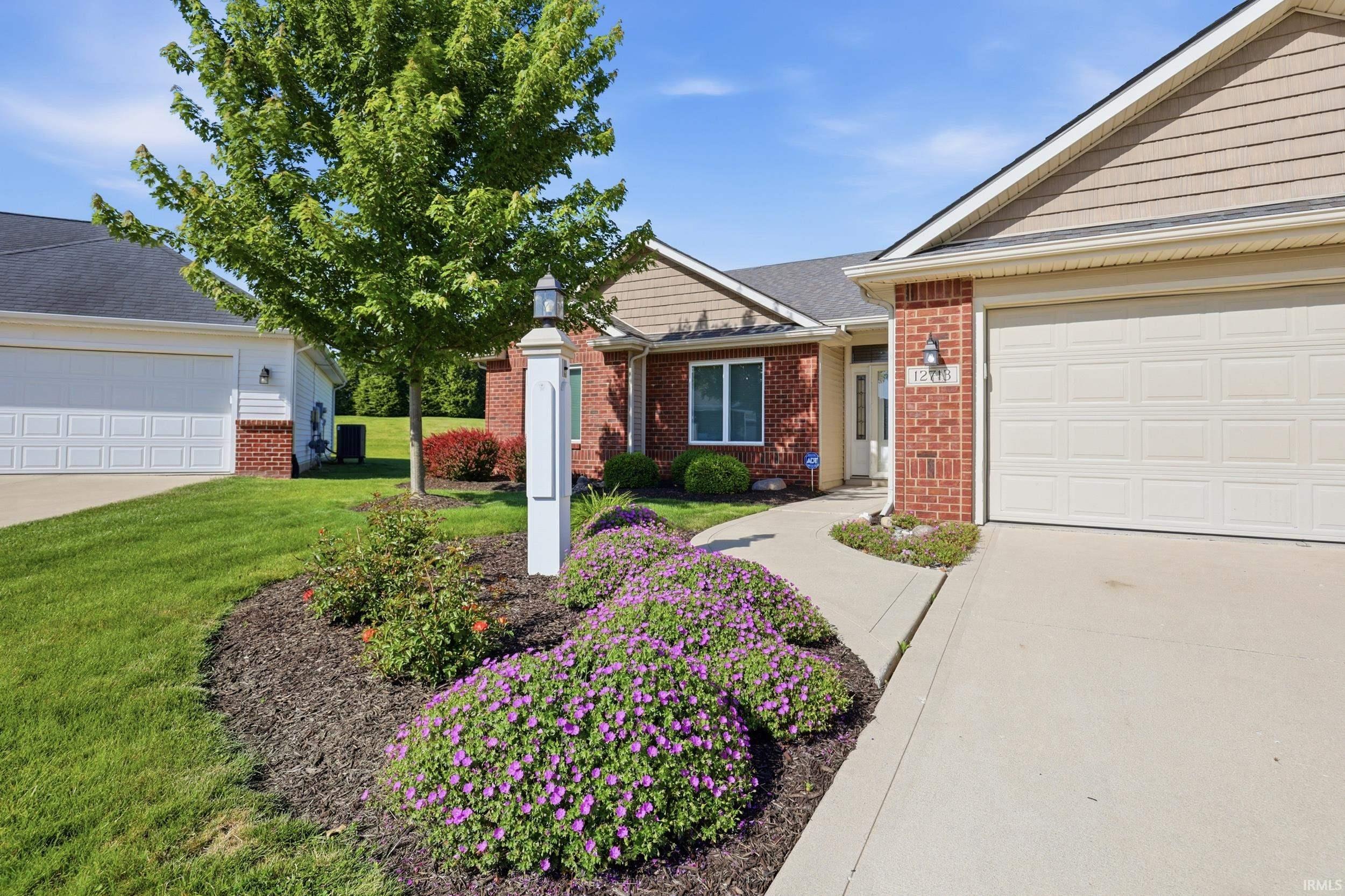 Brick exterior with tan siding accents, featuring a concrete driveway and sidewalk