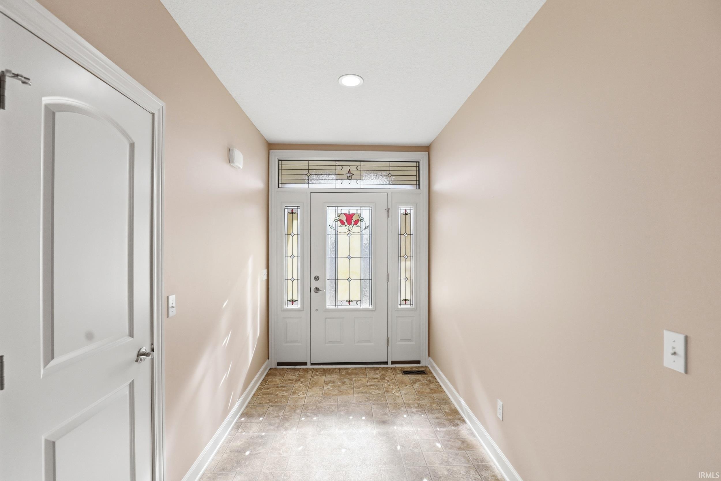Entryway featuring a white paneled door with decorative glass, sidelights, and a transom window