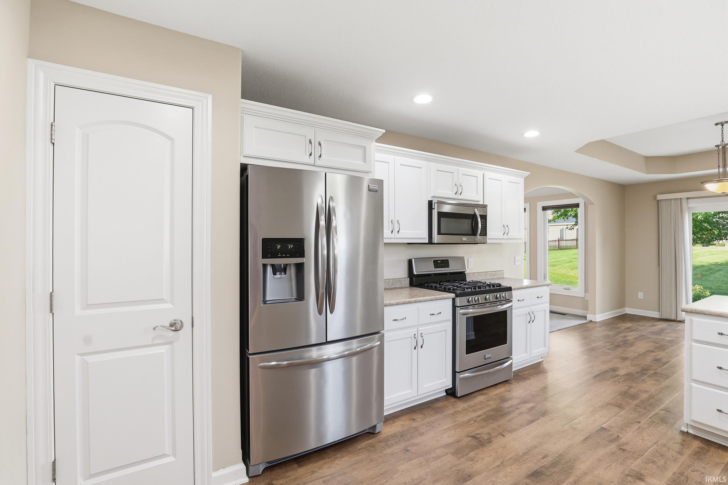 Kitchen featuring wood-finish flooring, white cabinetry, stainless steel appliances, and recessed lighting