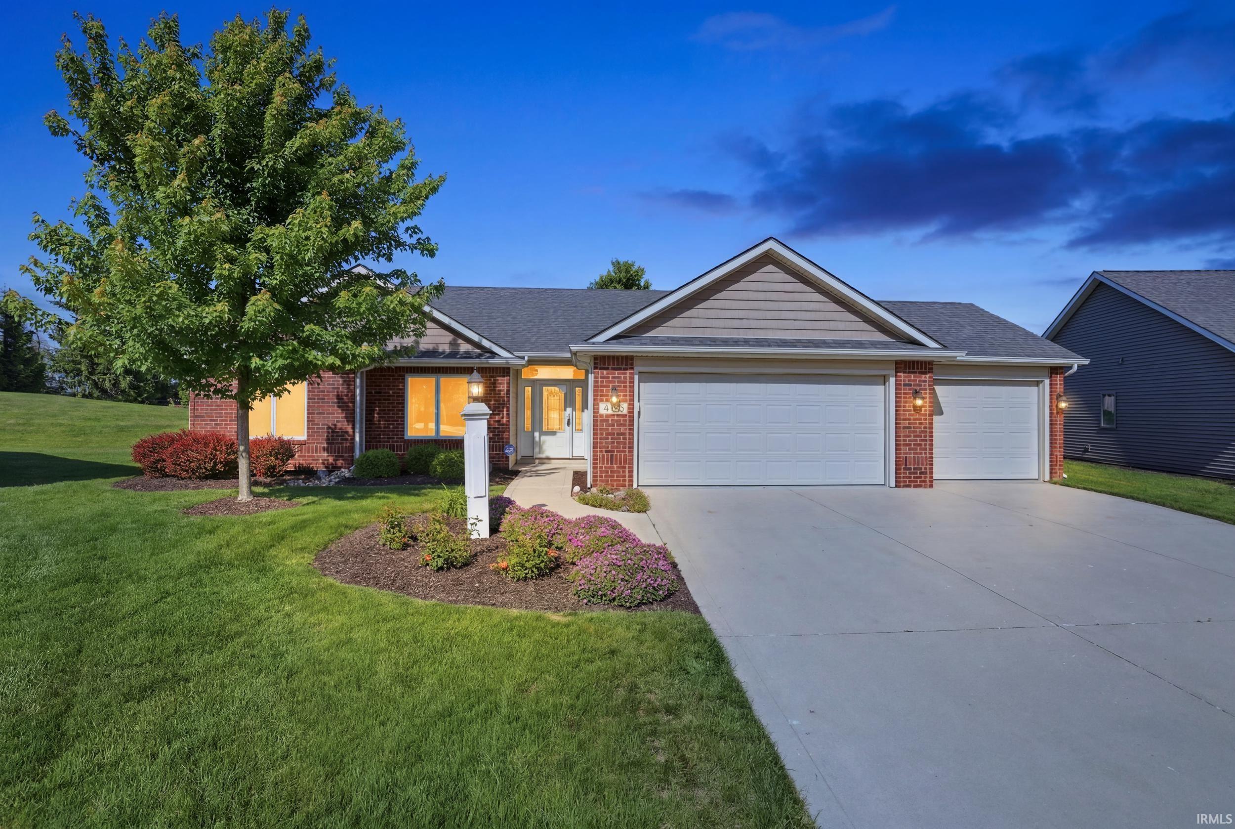 Brick and siding exterior featuring a two-car garage, concrete driveway, and front landscaping