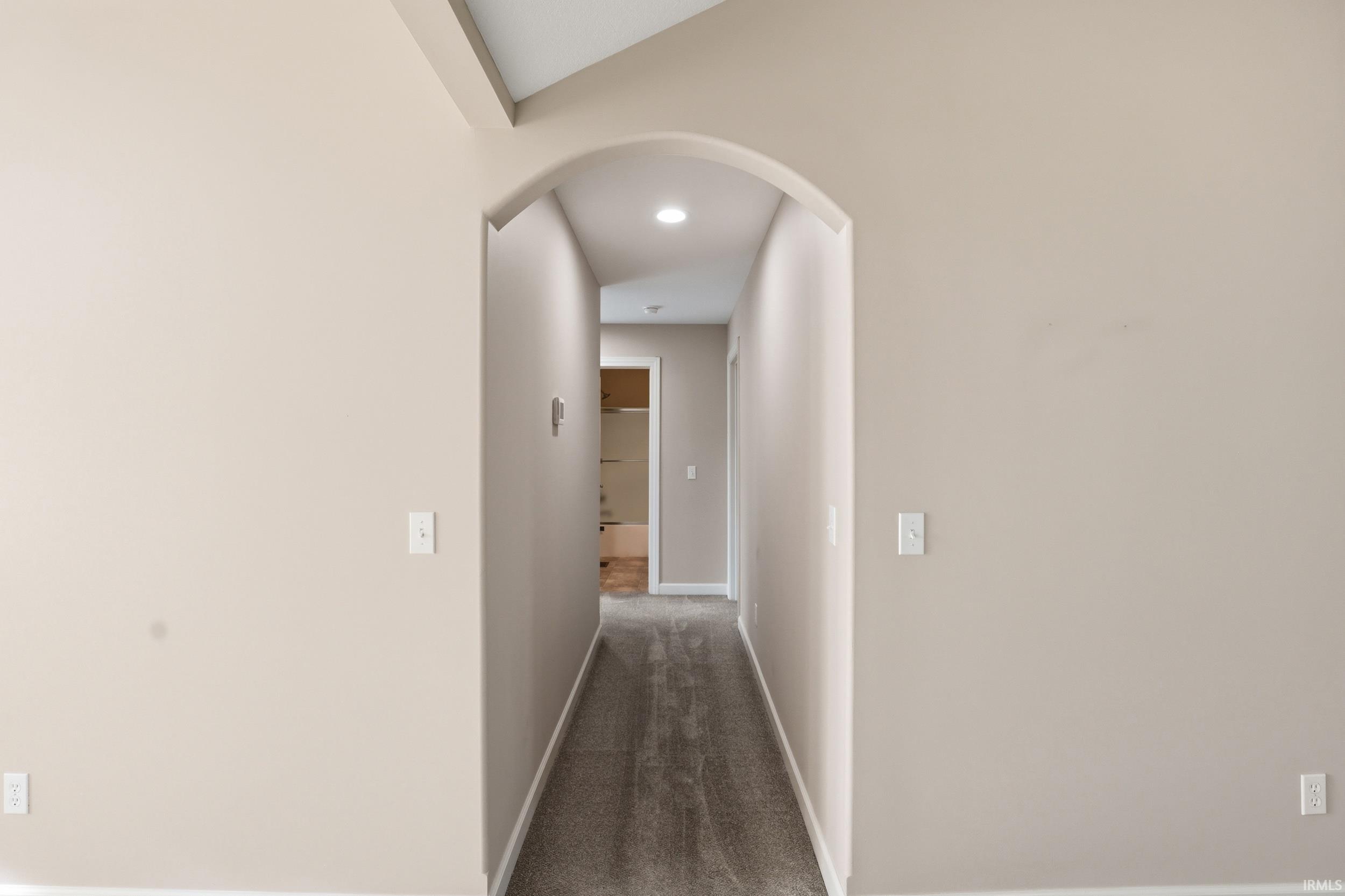 Archway entry to a carpeted hallway featuring recessed lighting, light neutral wall paint, and white trim