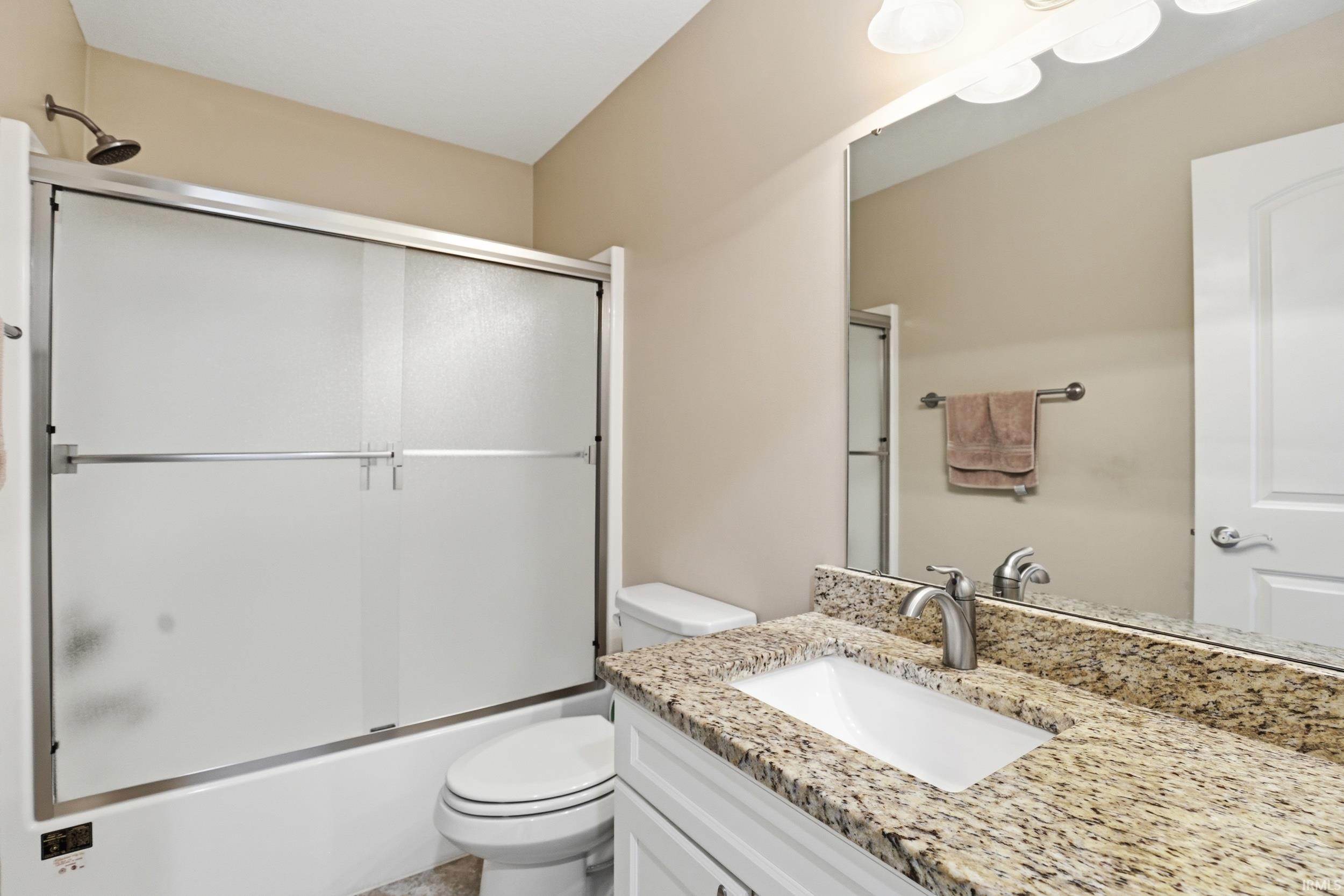 Bathroom featuring a vanity with a granite countertop, undermount sink, and brushed nickel faucet