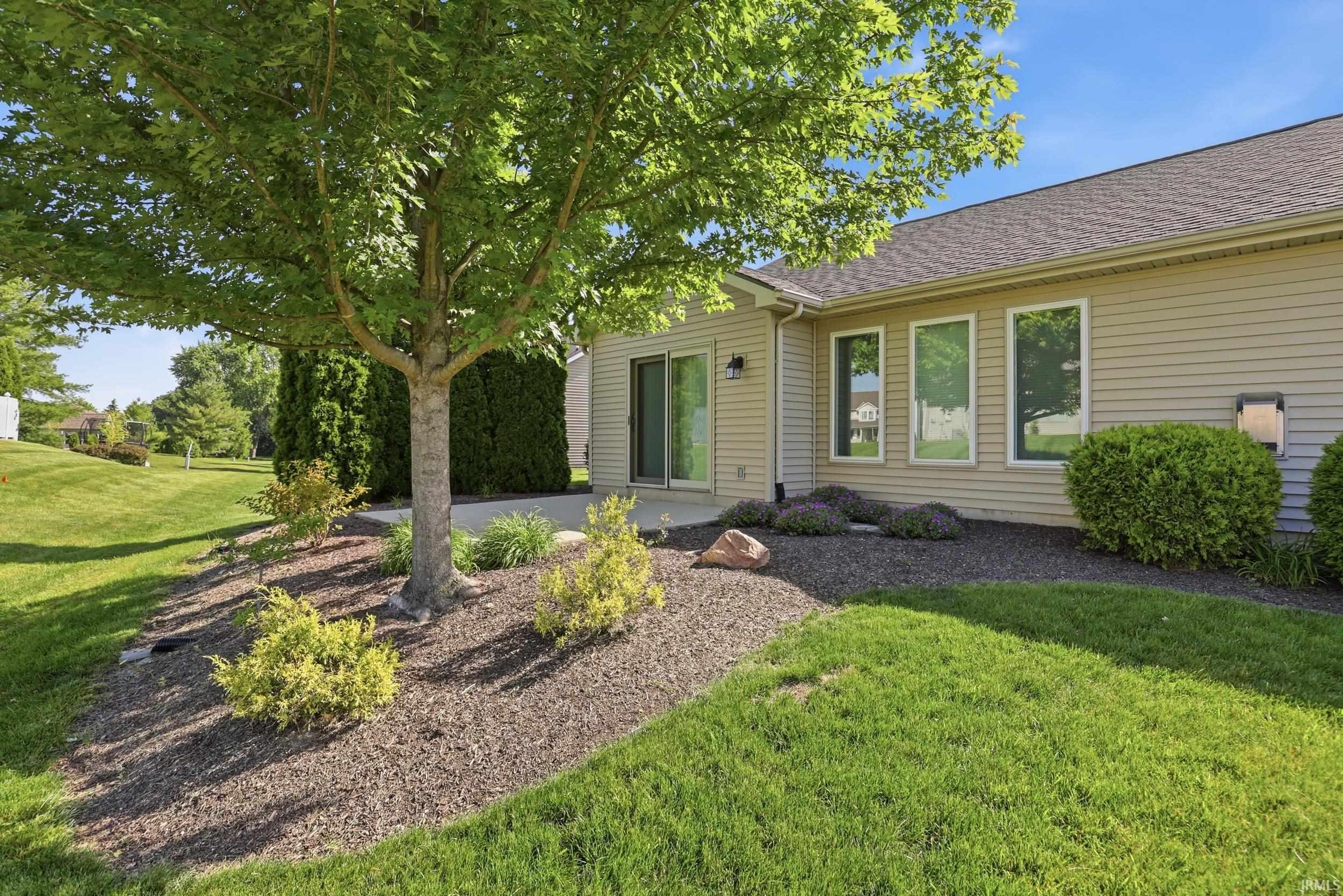 Rear exterior featuring tan siding, a concrete patio, and a shingle roof