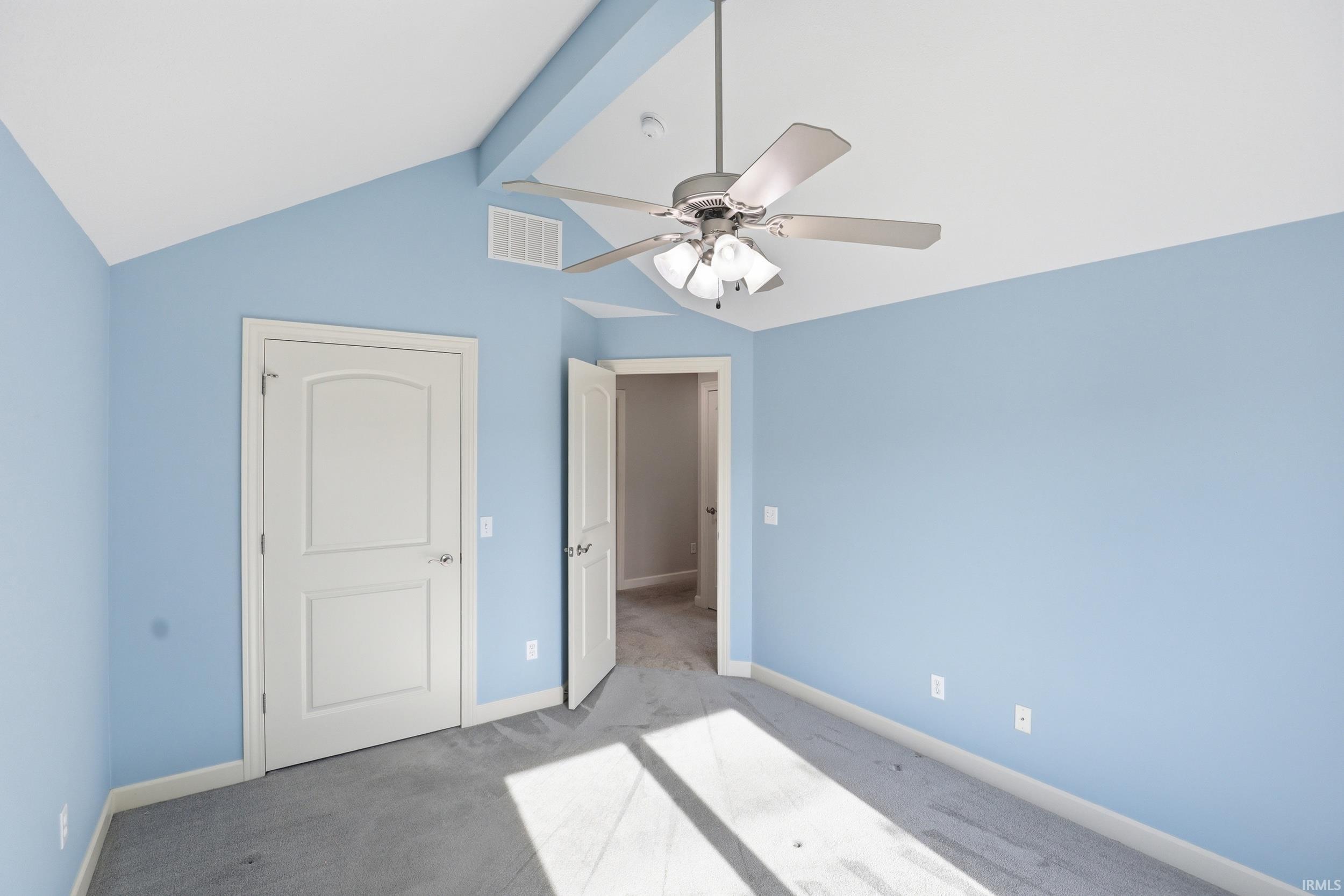 Vaulted ceiling with an exposed beam, light blue painted walls, and a ceiling fan with integrated lighting