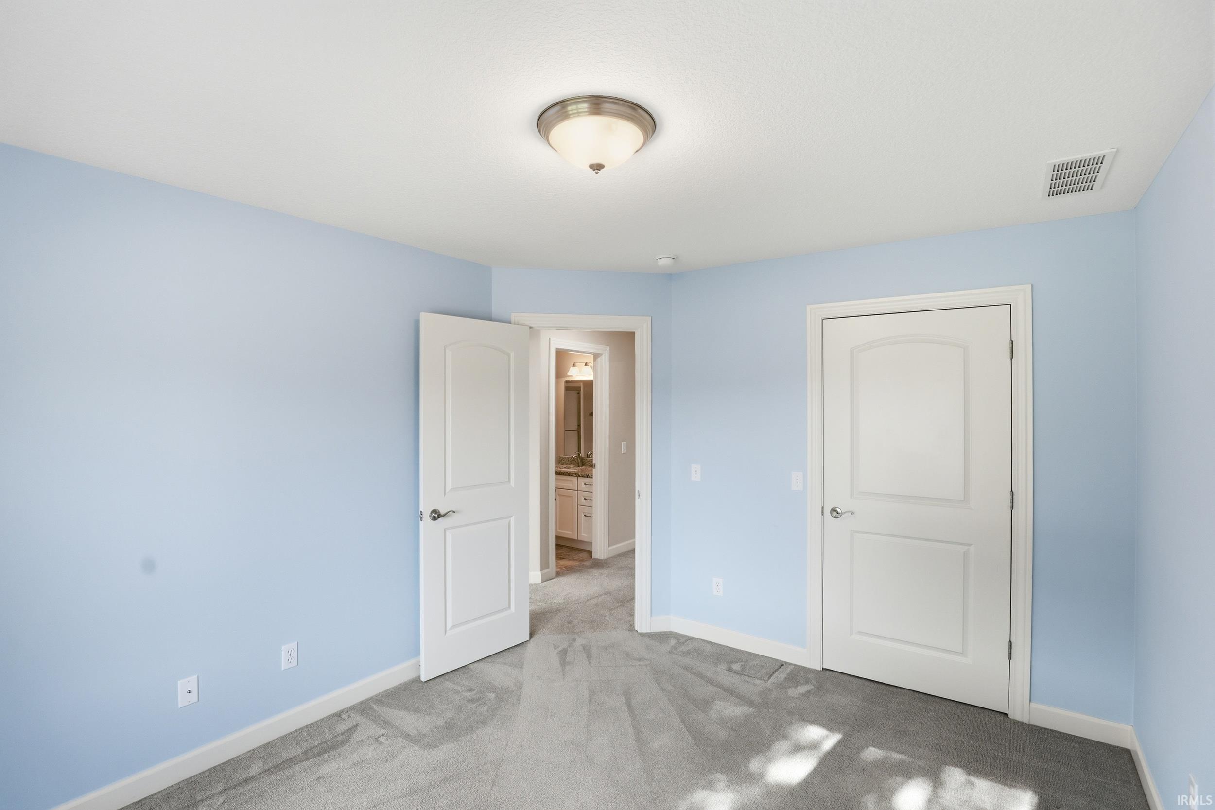 Room featuring light blue walls, gray carpet, and white trim