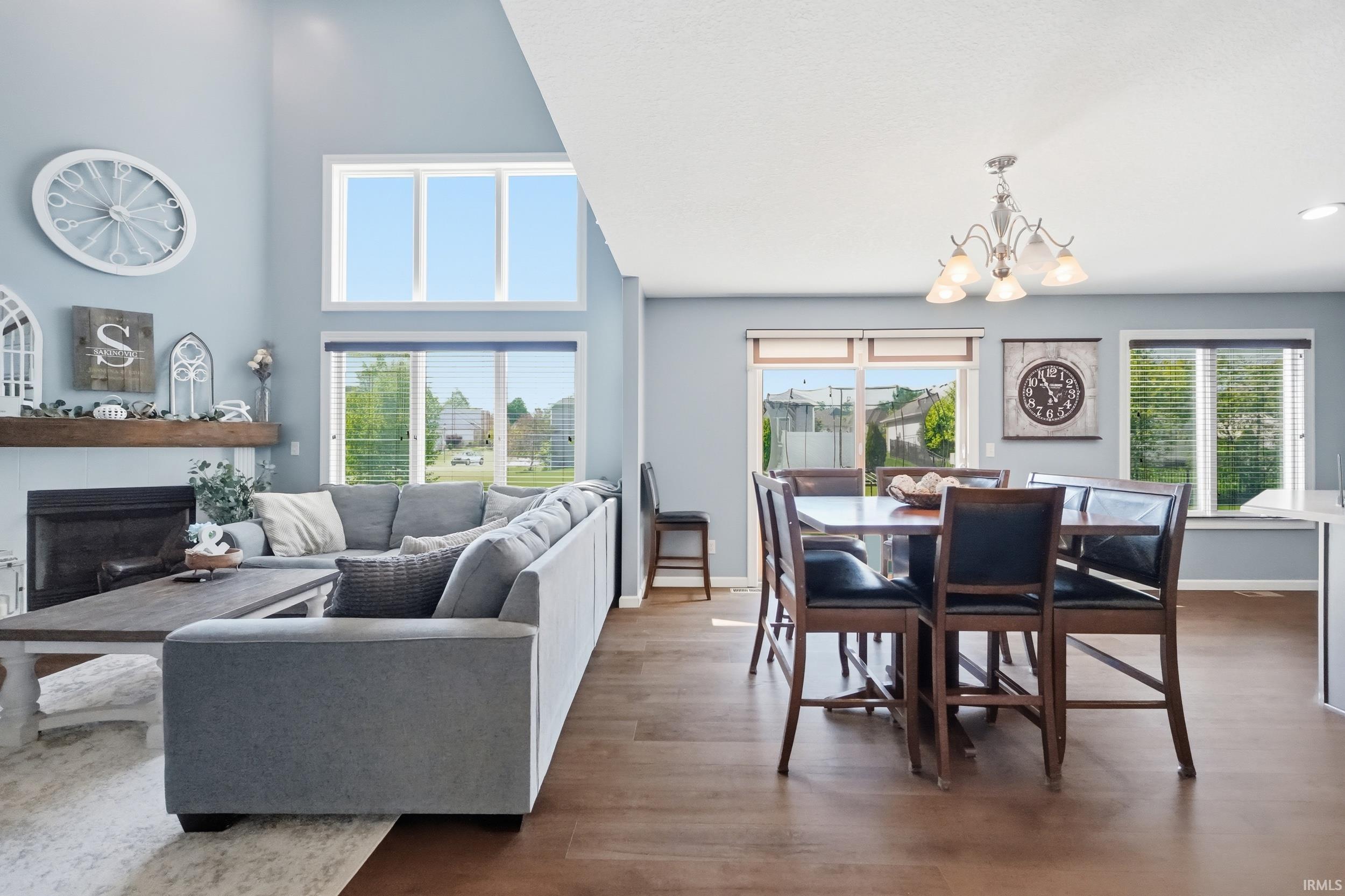 Open-concept living space featuring high ceilings, a fireplace with a wood mantel, and large windows