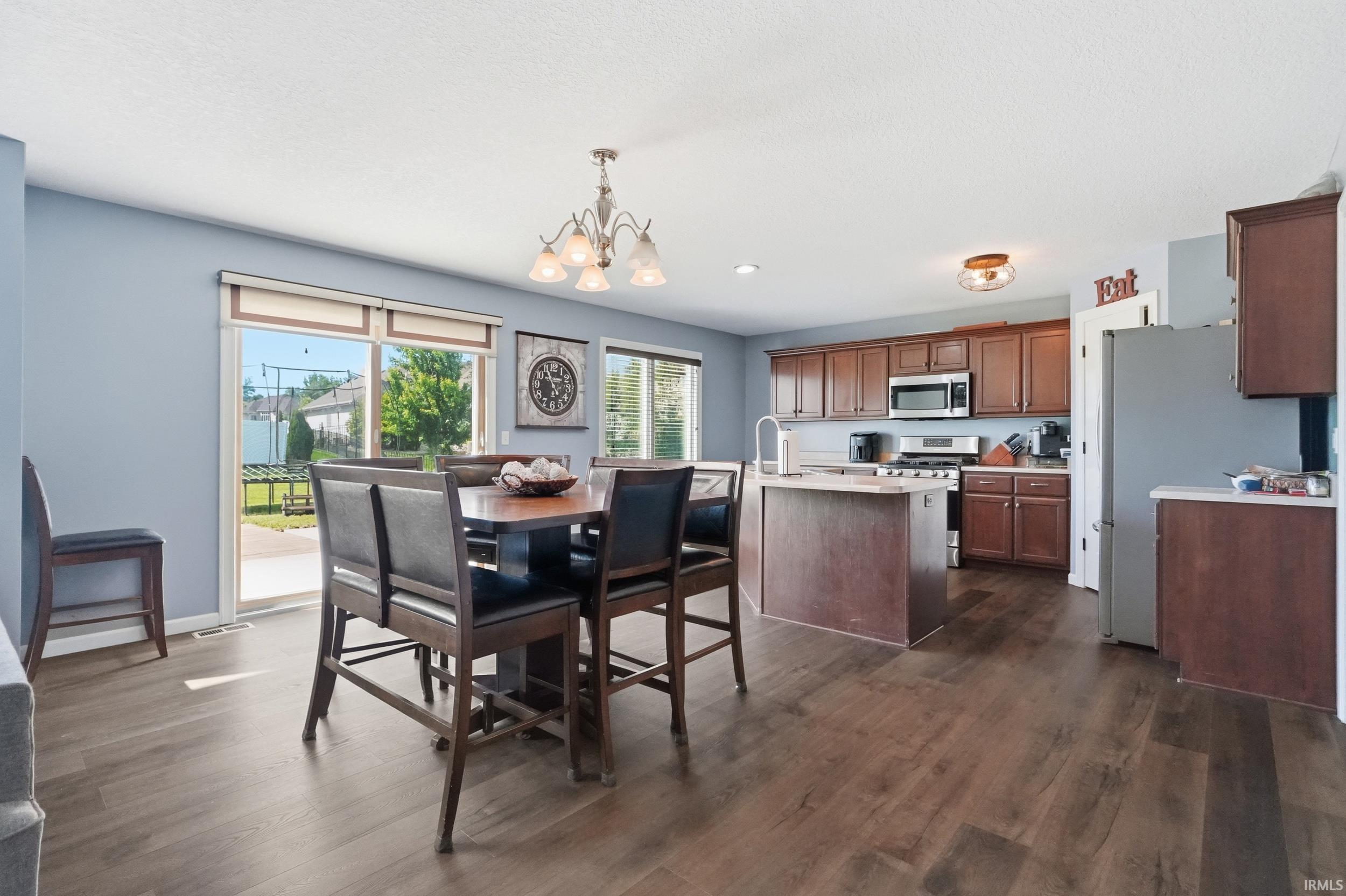 Open-concept kitchen and dining area featuring wood-finish flooring, wood cabinetry, and stainless steel appliances