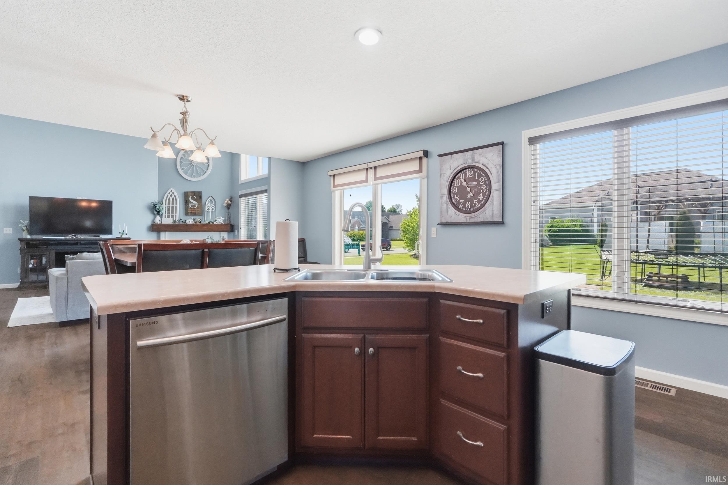 Kitchen island featuring a stainless steel sink, integrated dishwasher, and rich wood cabinetry