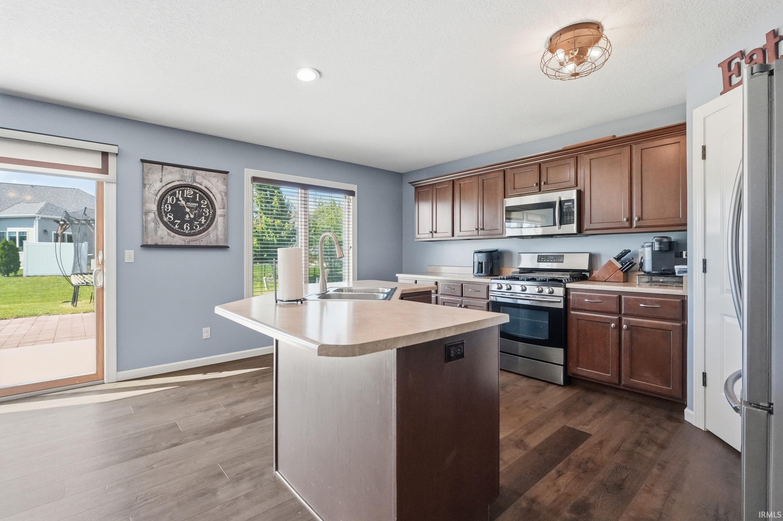 Kitchen featuring rich wood cabinetry, stainless steel appliances, a center island with countertop seating, and wood-finish flooring