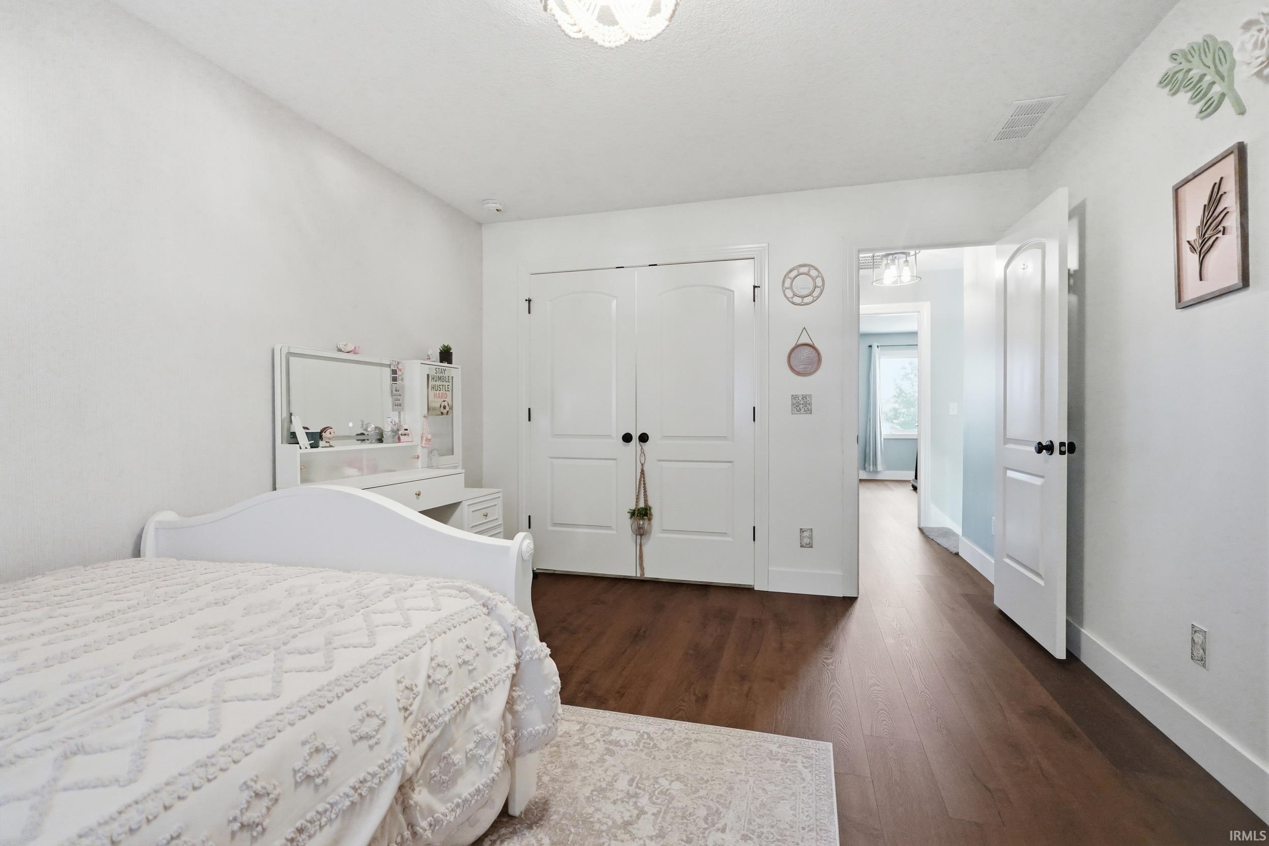 Bright room featuring wood-finish flooring, white walls, and a built-in double-door closet