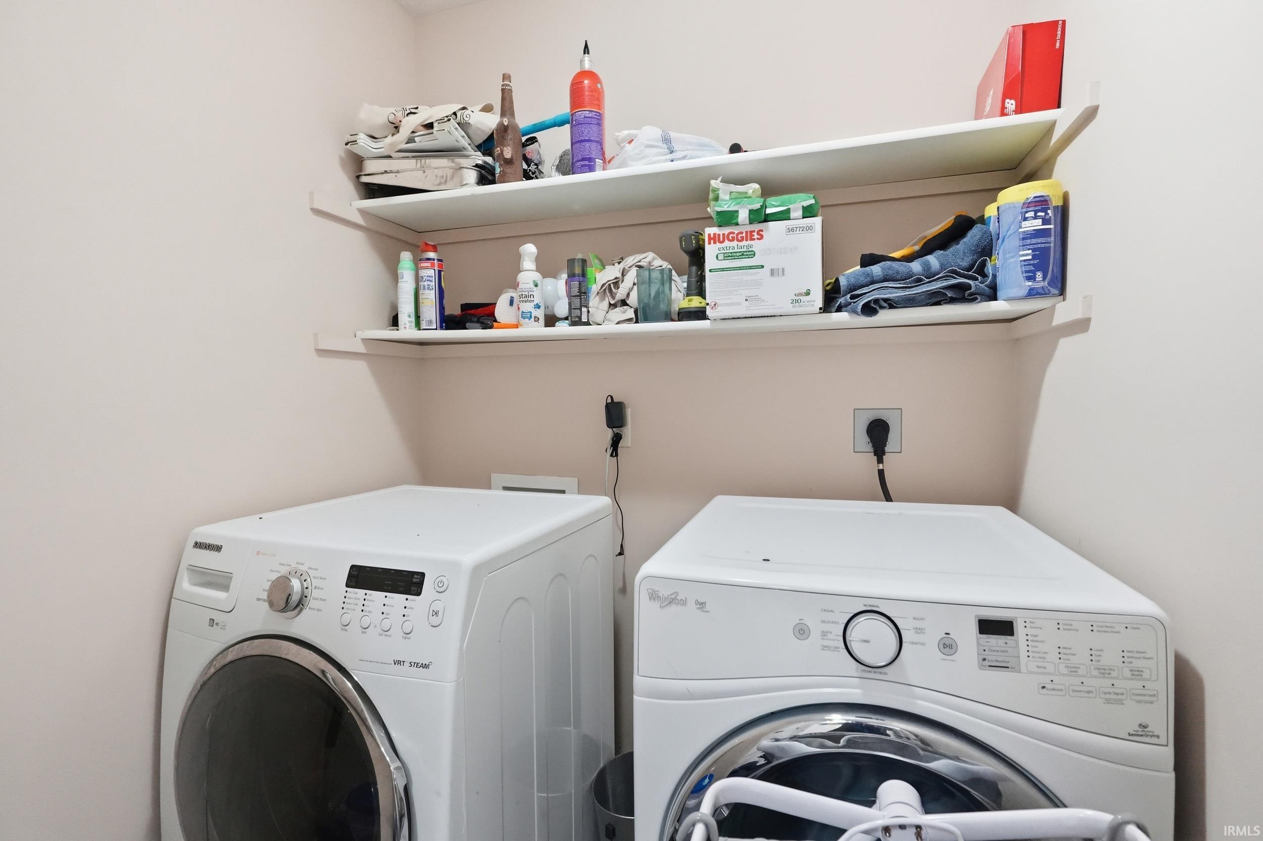 Dedicated laundry area featuring dual appliances and built-in wall shelving
