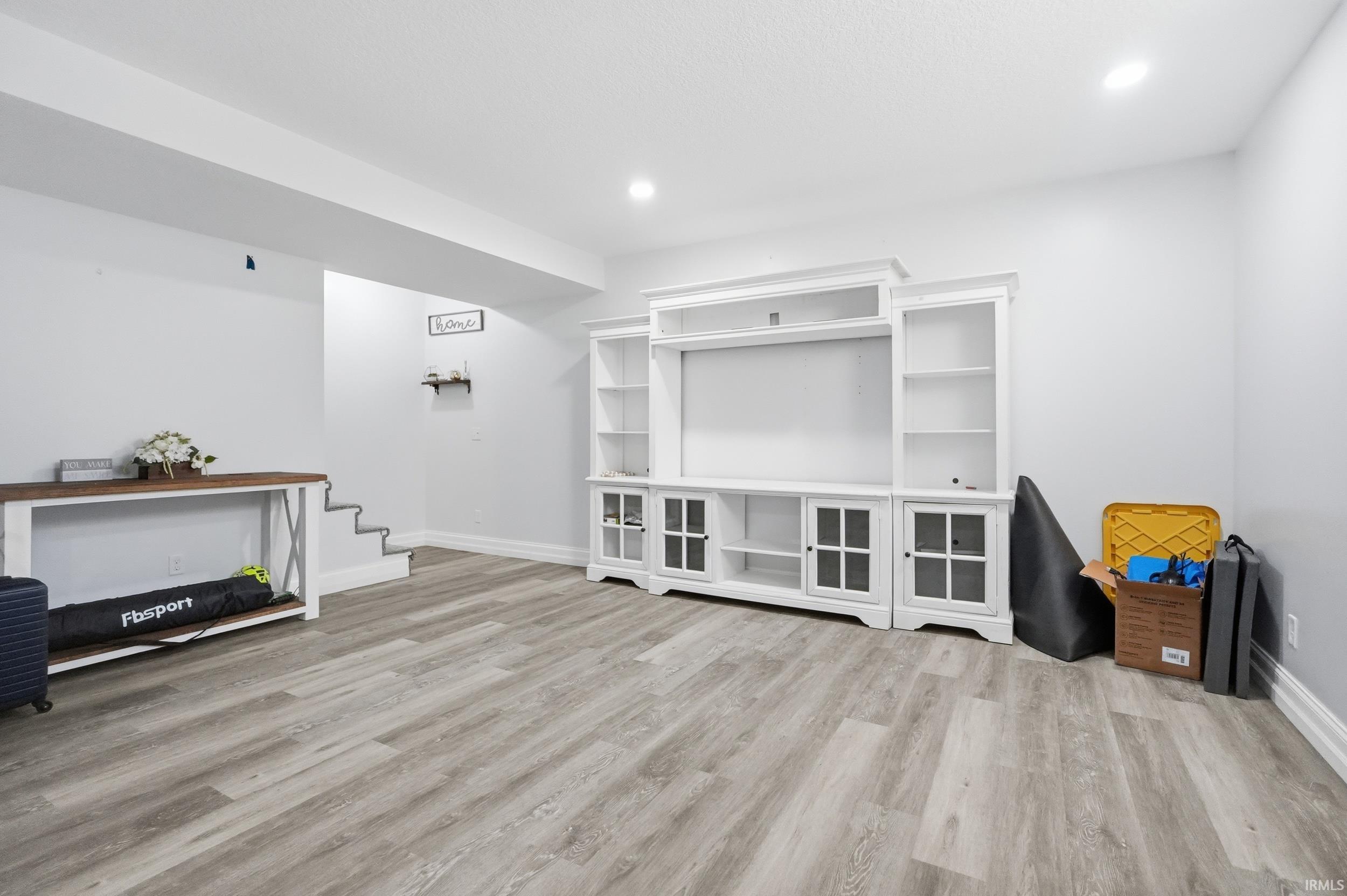 Spacious room featuring wood-finish flooring and recessed lighting