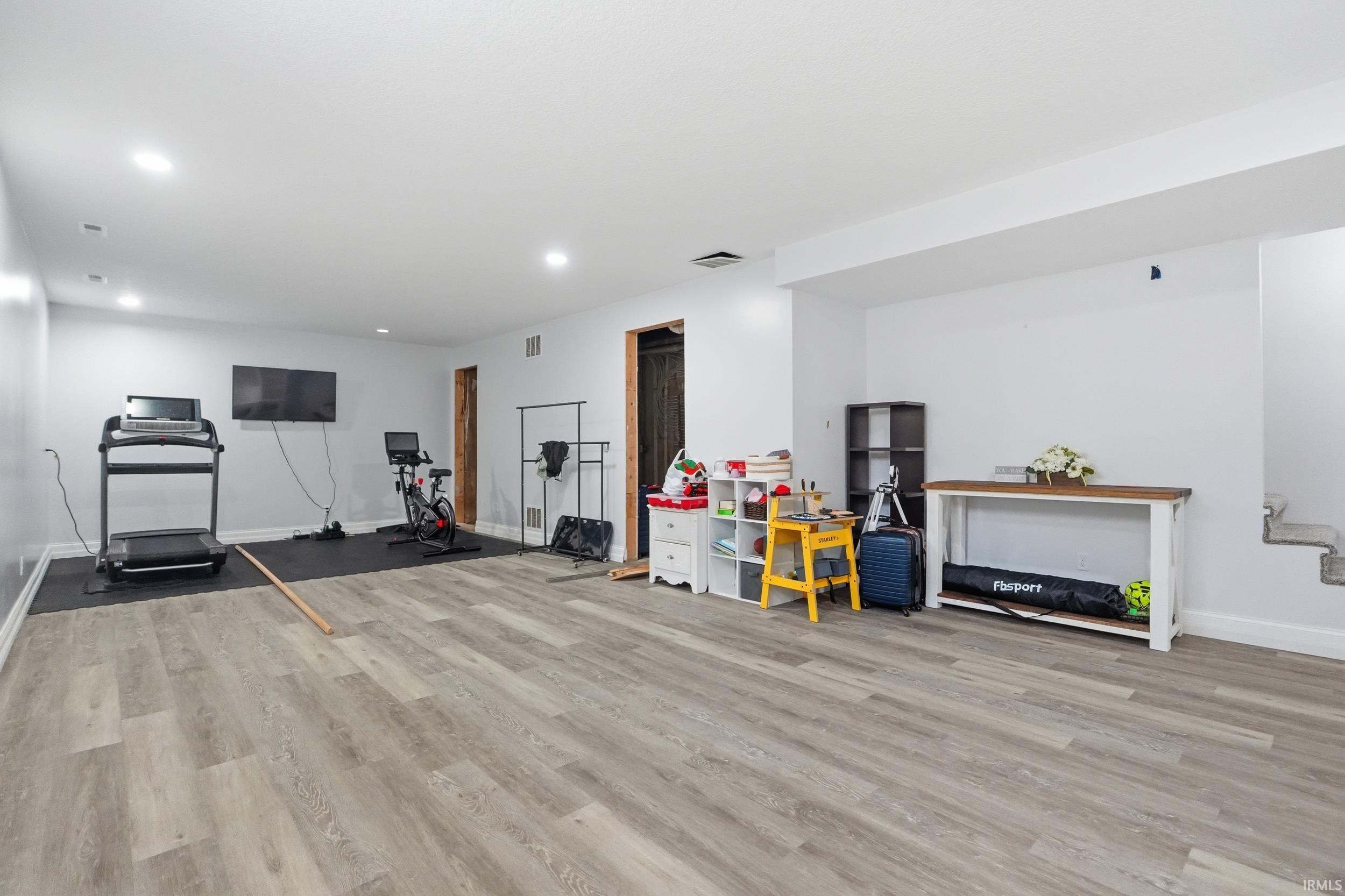 Spacious room featuring light wood-finish flooring, recessed lighting, and white walls