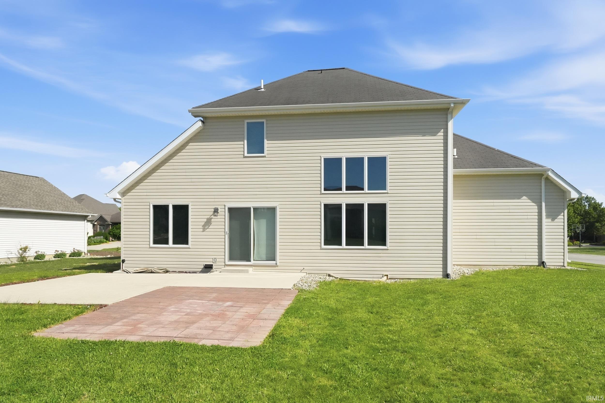 Rear exterior featuring beige horizontal siding, a dark shingle roof, a sliding glass door, and multiple large windows