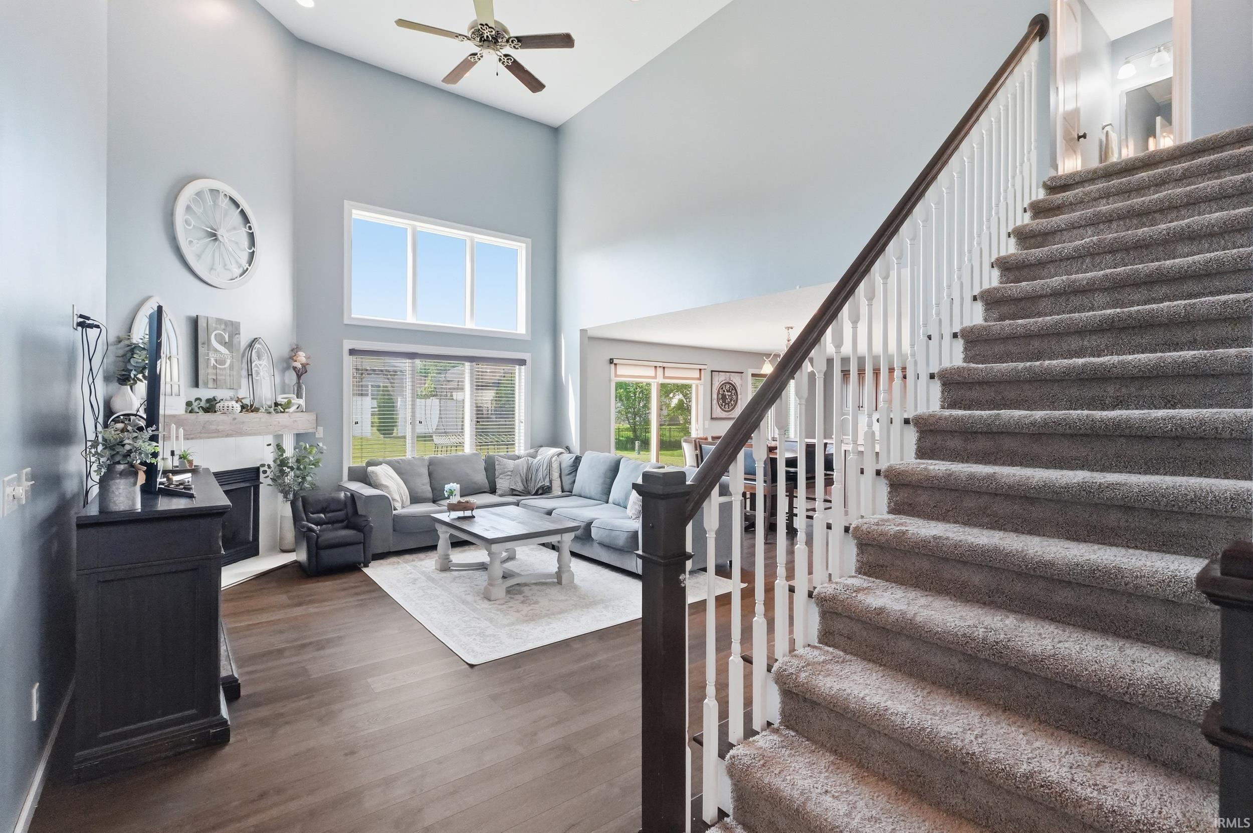 Two-story living area featuring a corner fireplace, wood-finish flooring, and a bank of windows
