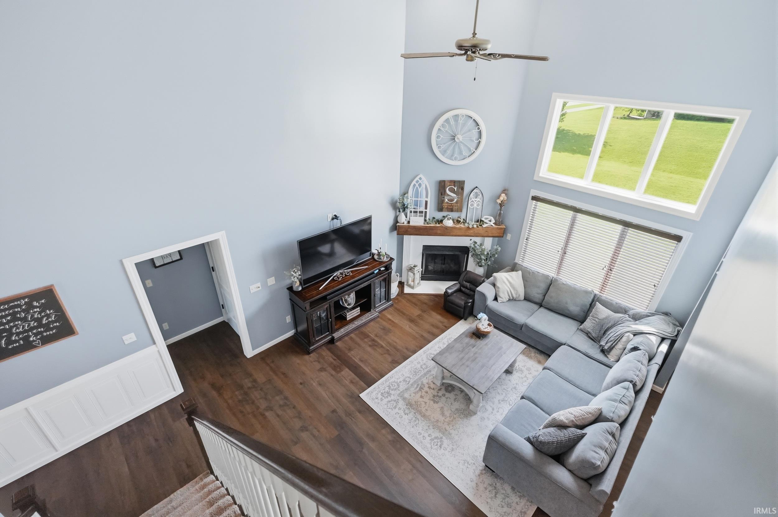Two-story living area featuring wood-finish flooring and a fireplace with a wood mantel