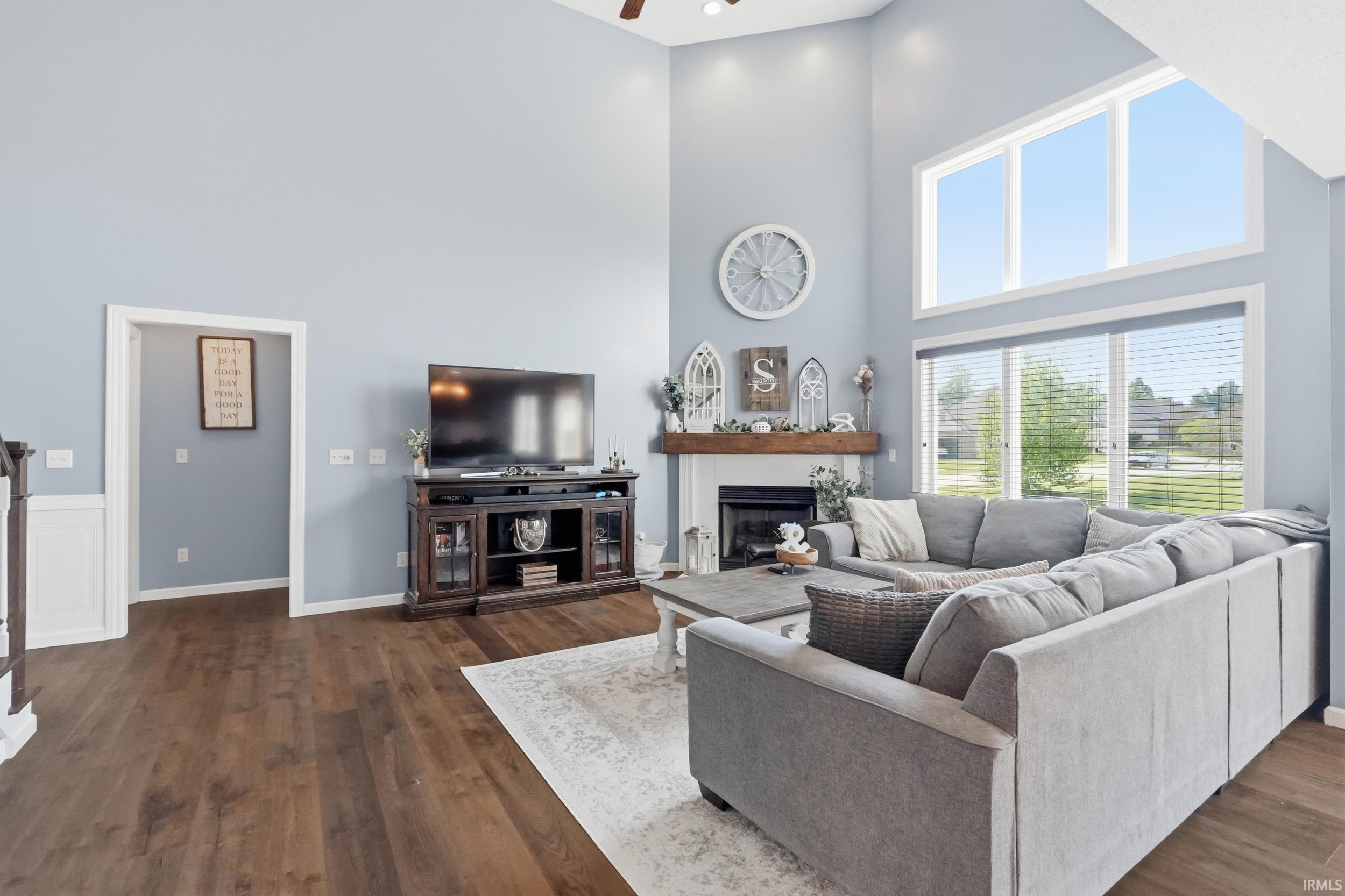 Vaulted living room featuring wood-finish flooring and a white-trimmed fireplace with a wood mantel
