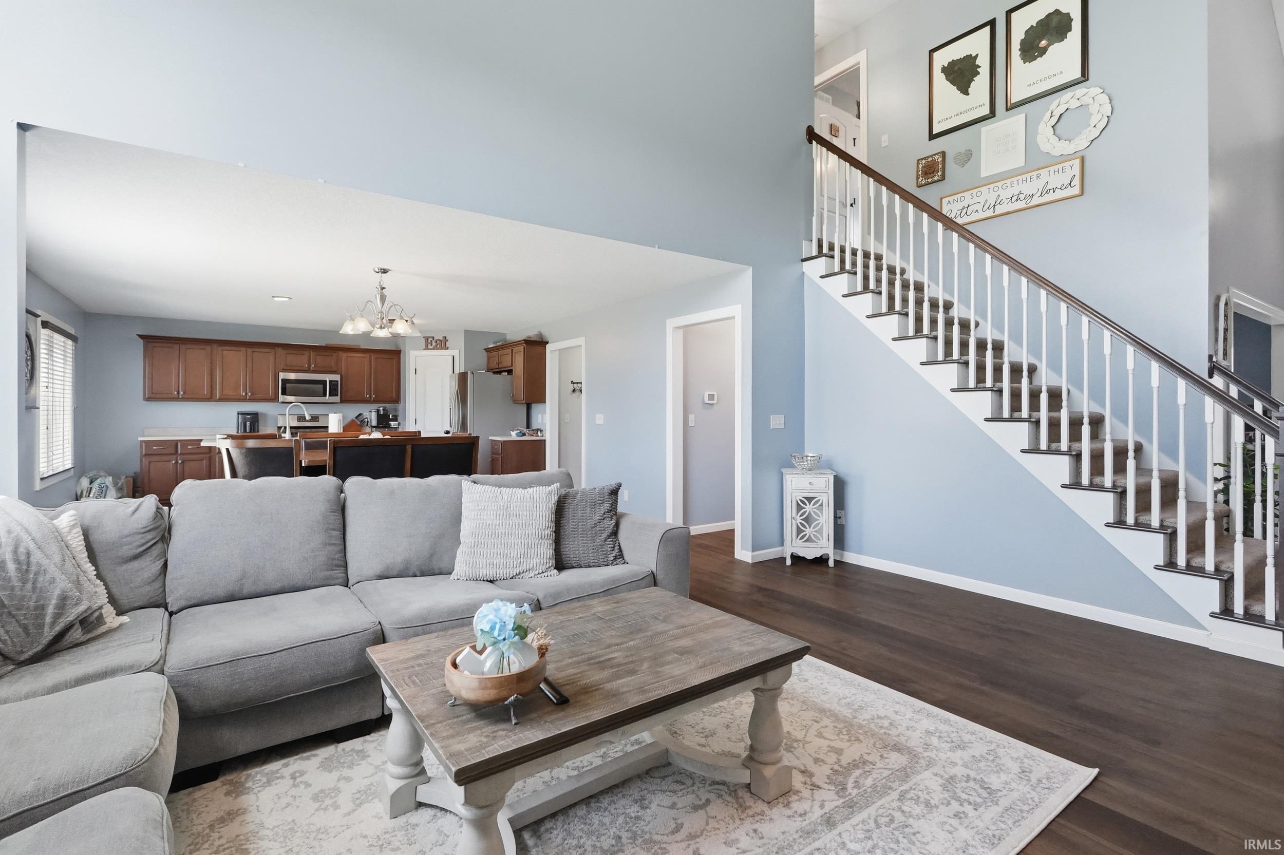 Open concept living area with dark wood-finish flooring extending to a staircase with white balusters and a dark wood handrail