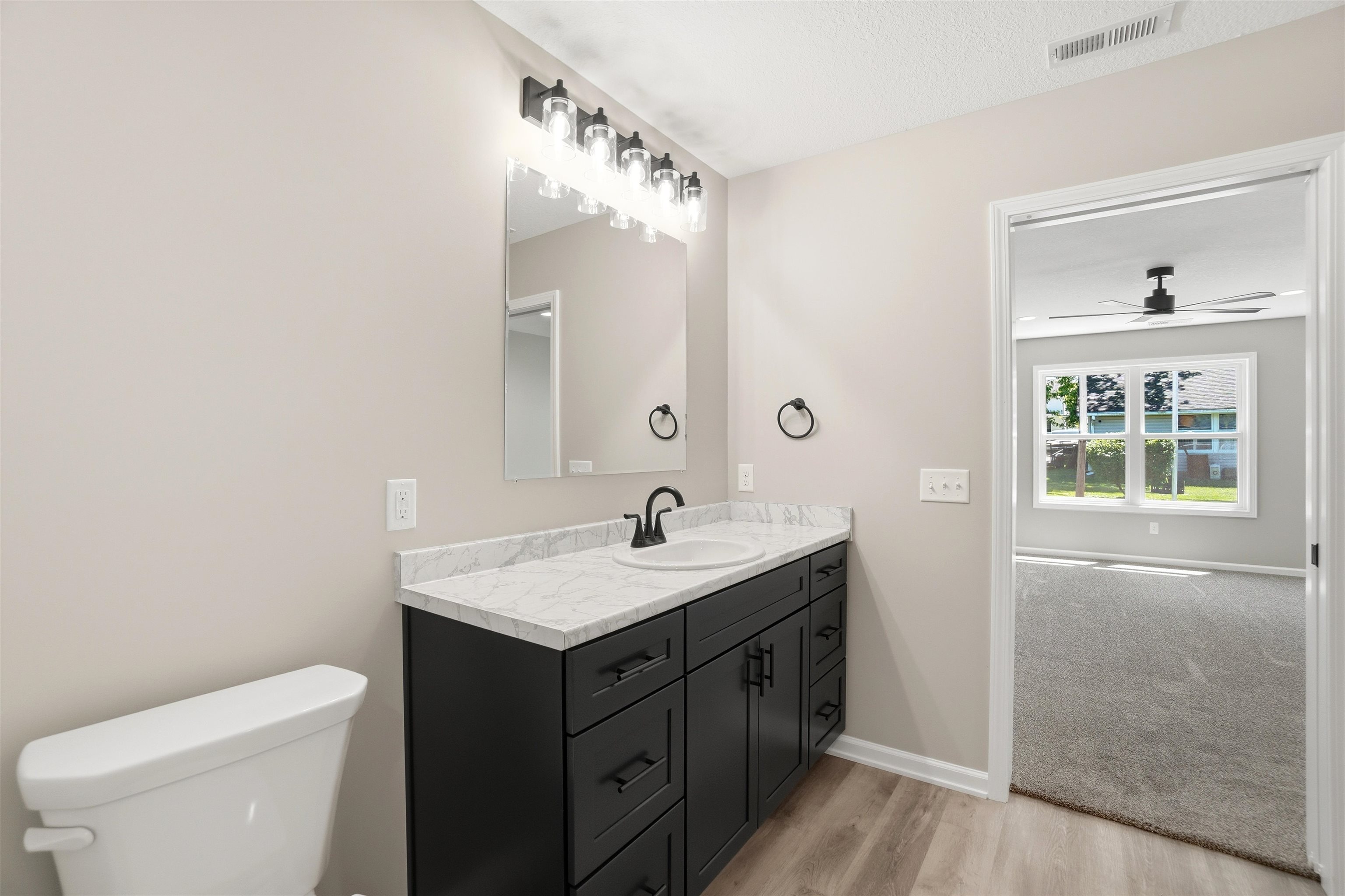 Bathroom vanity featuring a dark wood-finish cabinet, white countertop, and a single basin sink with a black faucet