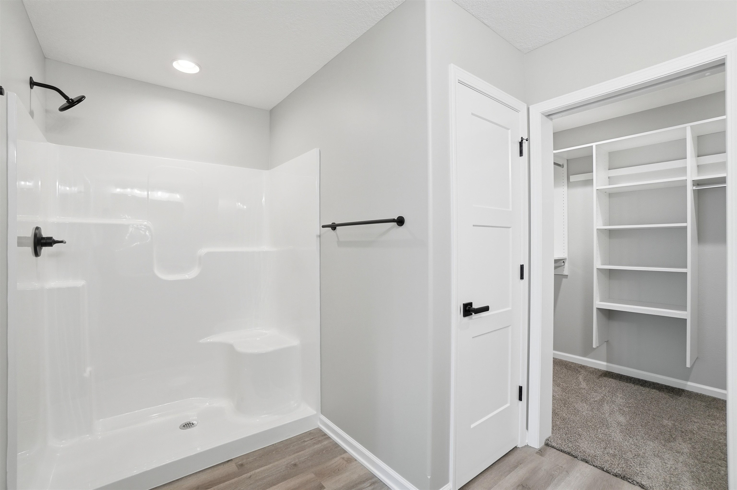 Shower with integrated seating, matte black fixtures, and recessed lighting