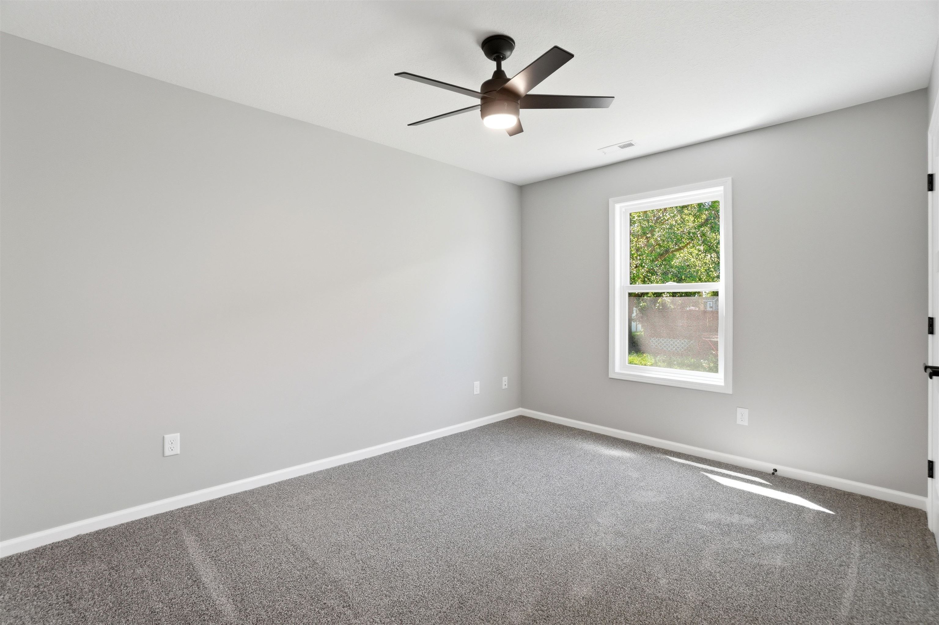 Spacious room featuring neutral grey wall paint and grey carpet flooring