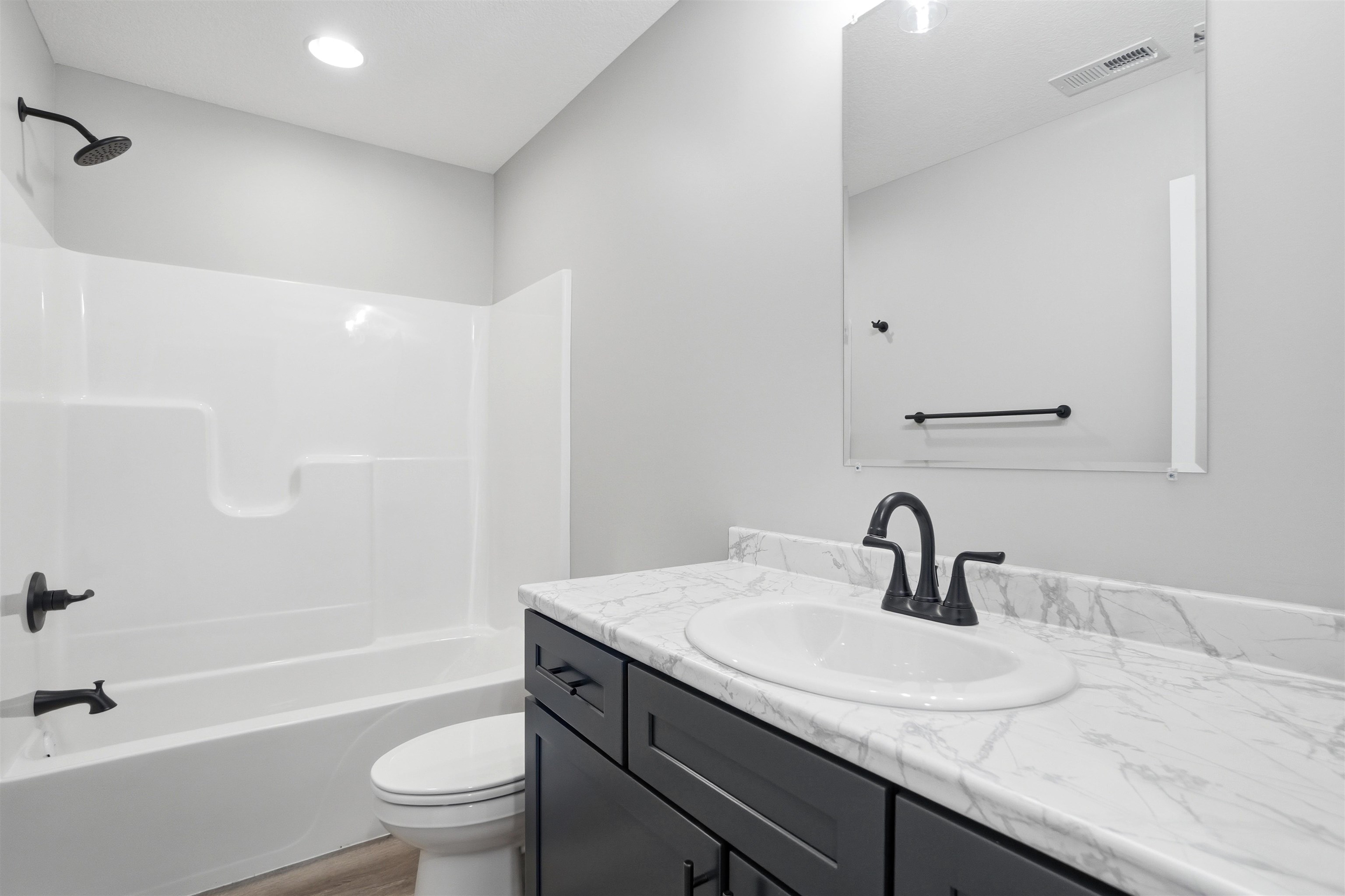 Bathroom featuring a vanity with a white oval sink, dark cabinetry, and a light-toned countertop