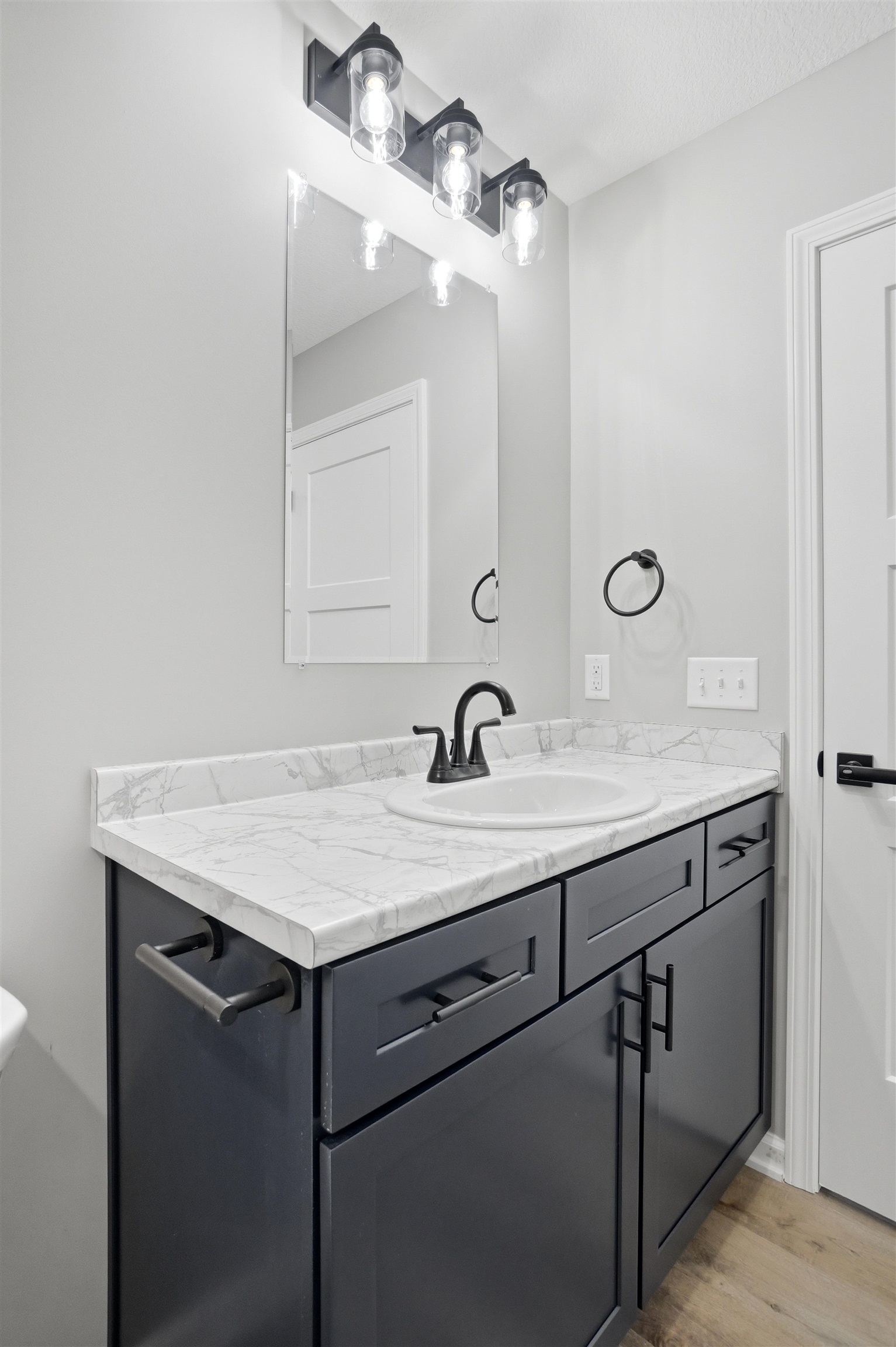 Vanity featuring a white countertop with subtle gray veining, an undermount sink, and a matte black faucet