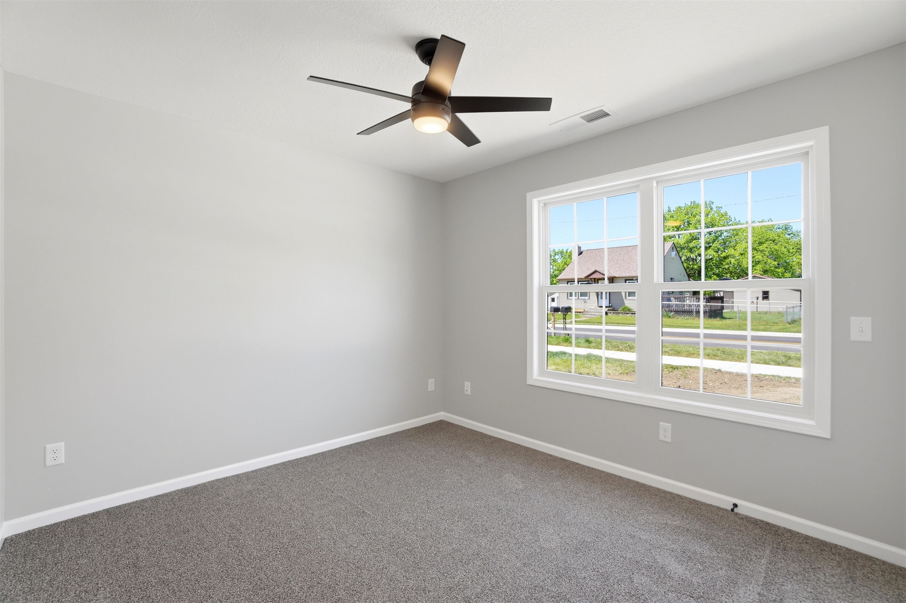 Room featuring a multi-pane window, neutral gray walls, white trim, and gray carpeting