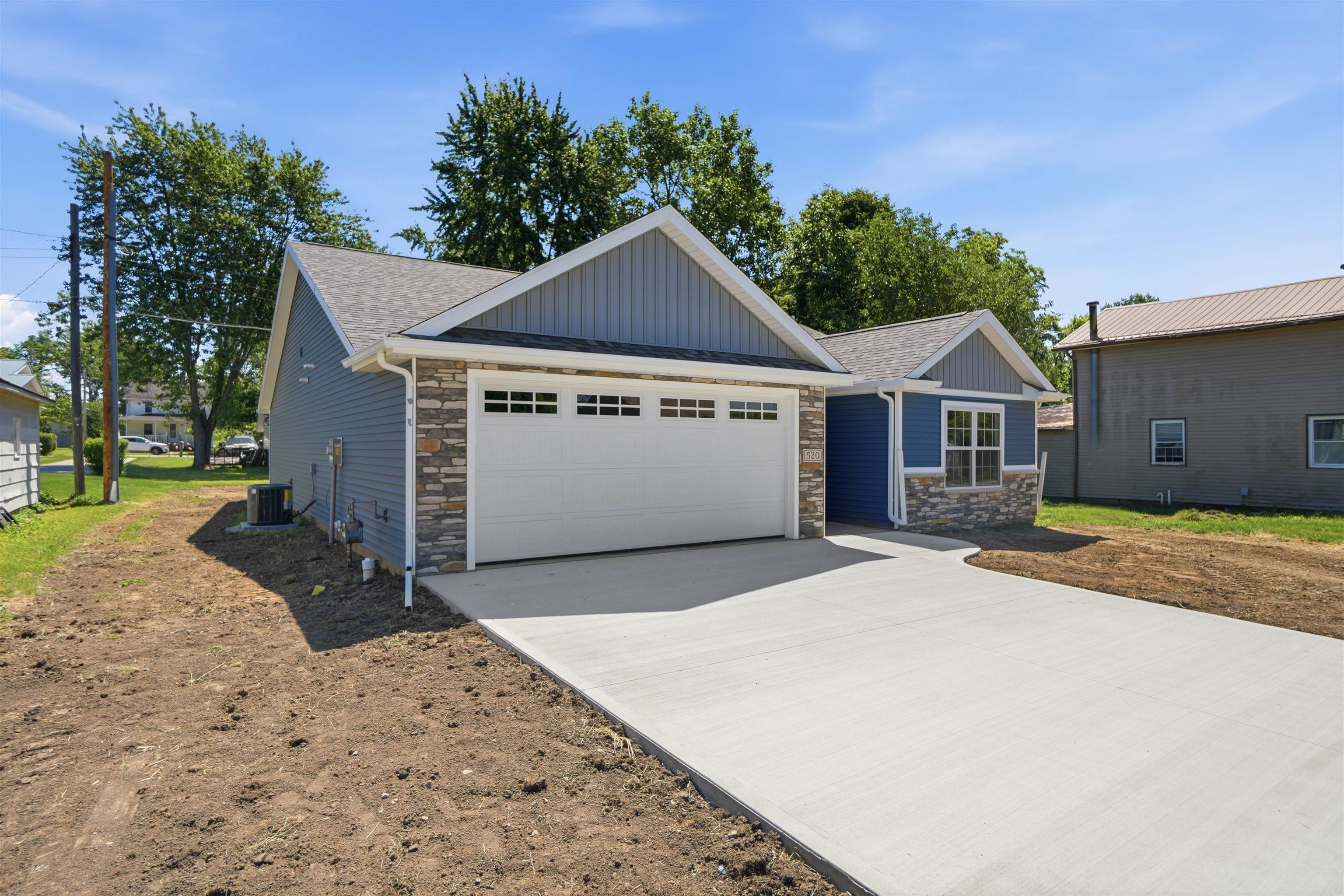Contemporary architecture featuring a light blue siding exterior, stone veneer accents, and a crisp white garage door with upper window inserts