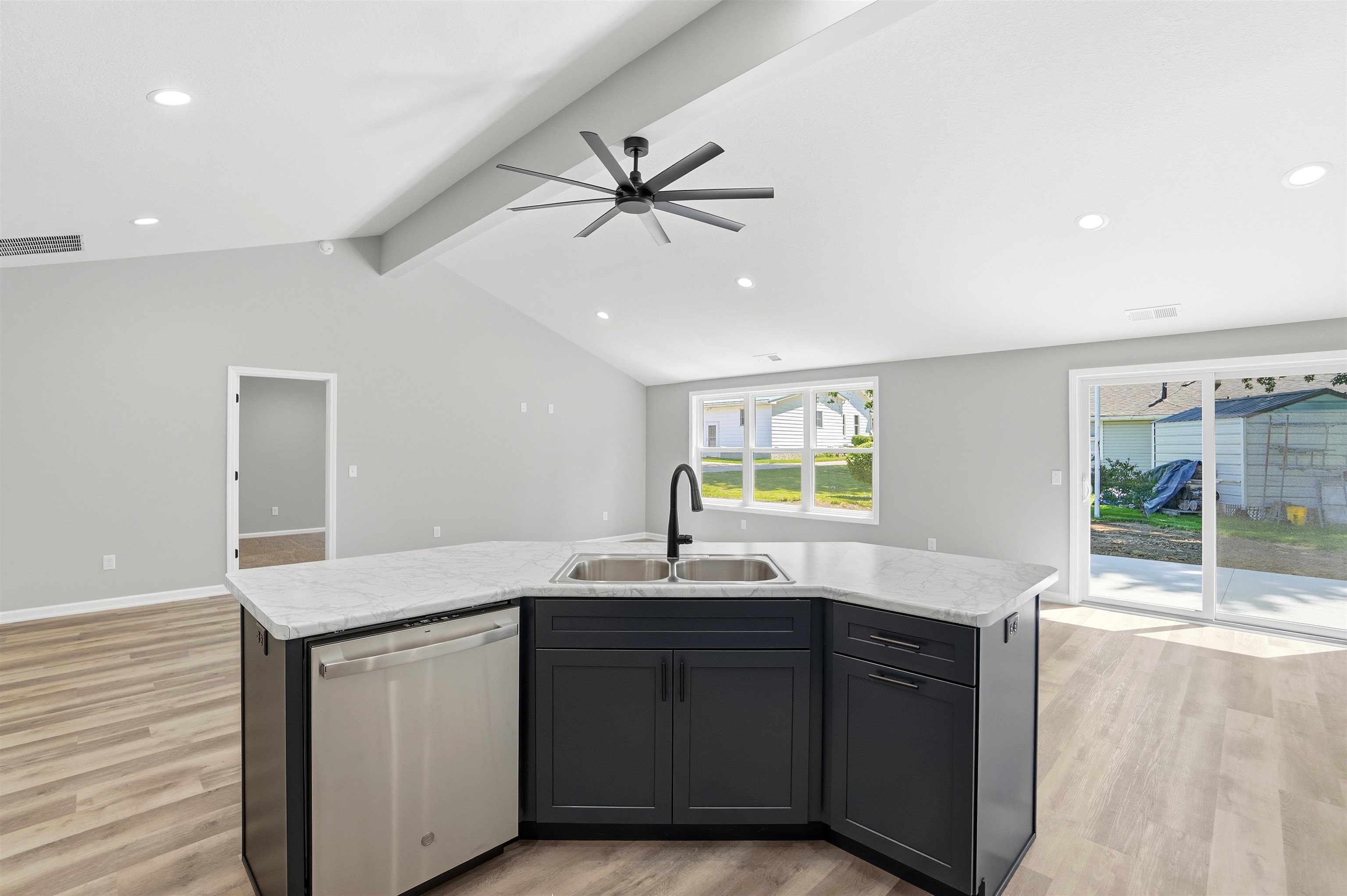 Central kitchen island featuring a double-basin sink with a matte black faucet, integrated dishwasher, and dark cabinetry