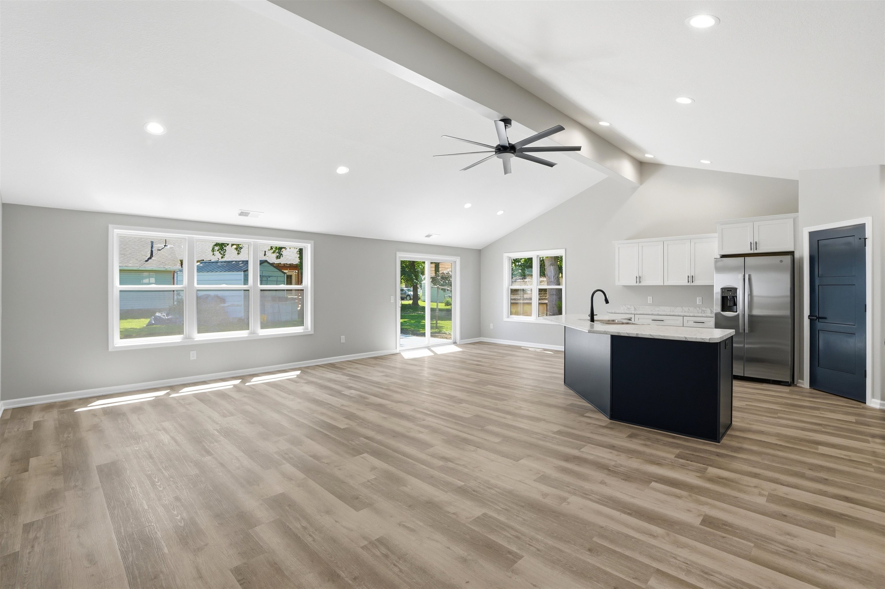 Open-concept living area featuring a vaulted ceiling with a contemporary ceiling fan, recessed lighting, and wood-finish flooring