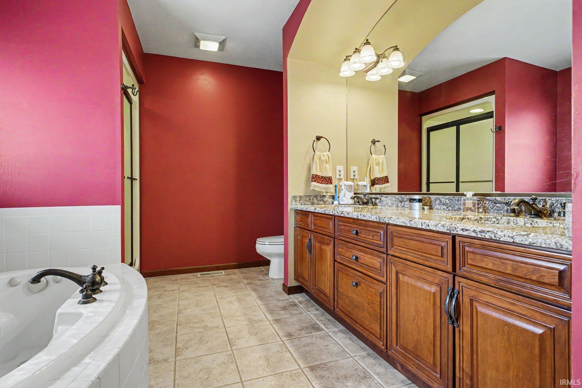 Dual sink vanity with stone-finish countertop, wood-finish cabinetry, and oil-rubbed bronze fixtures
