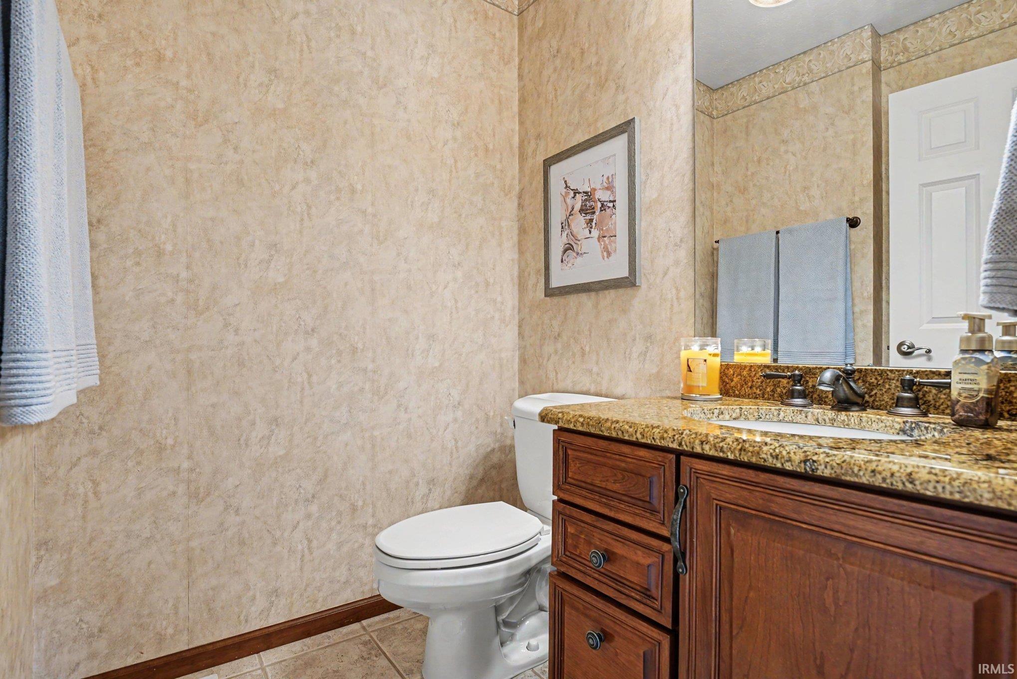Bathroom featuring a dark wood-finish vanity with an undermount sink, a stone-finish countertop, and bronze-finish hardware