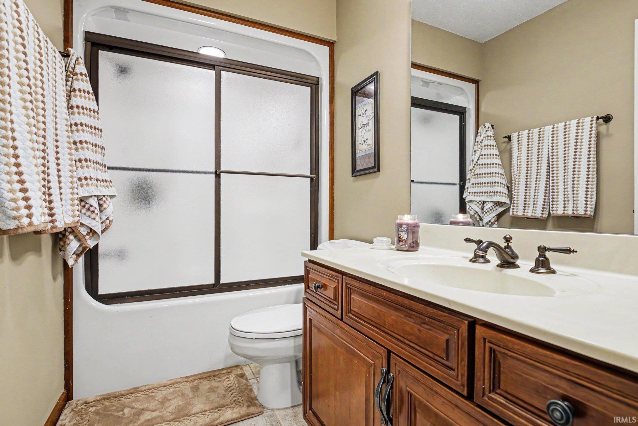 Bathroom featuring a wood-finish vanity with an integrated sink and bronze-finish fixtures