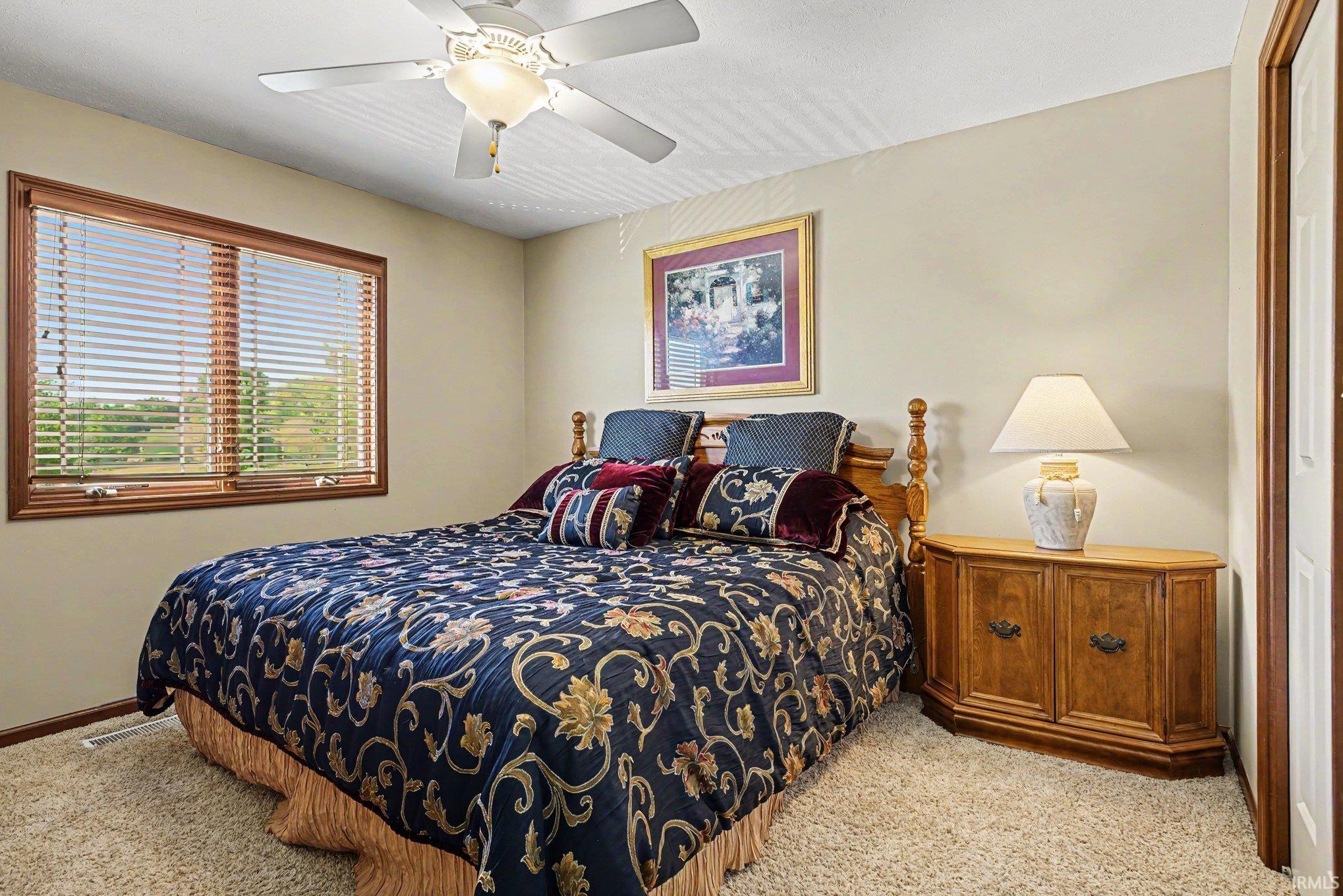 Carpeted room featuring a large window with wood trim, a ceiling fan, and painted walls
