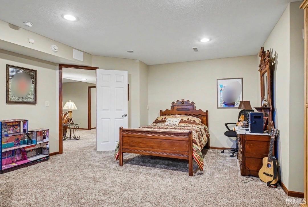 Carpeted room with recessed lighting and a white paneled door
