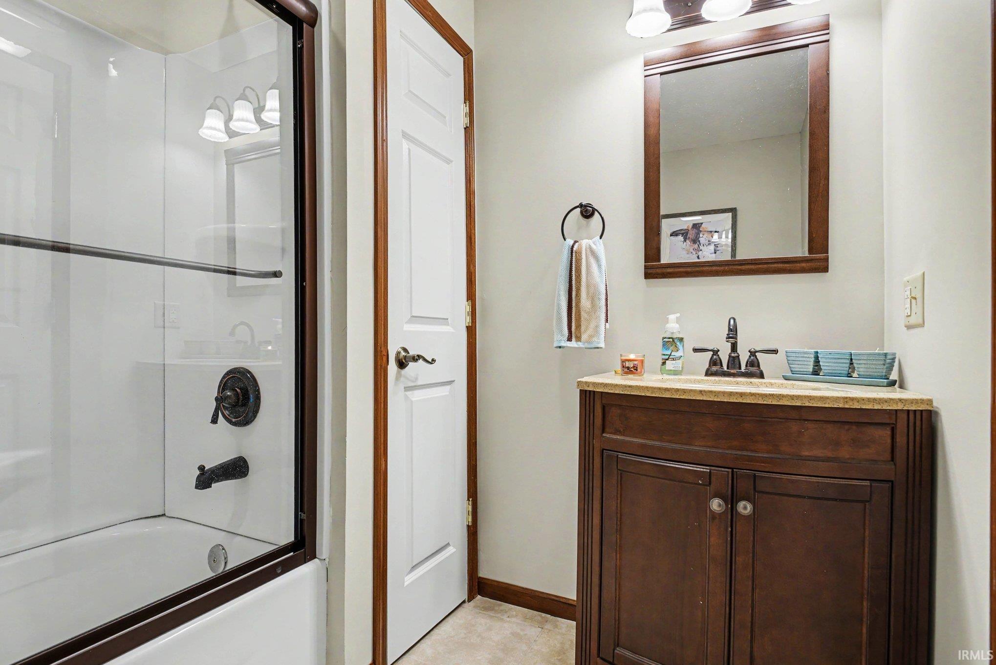 Bathroom featuring a dark wood vanity with a light-toned countertop, a framed mirror, and a three-light fixture
